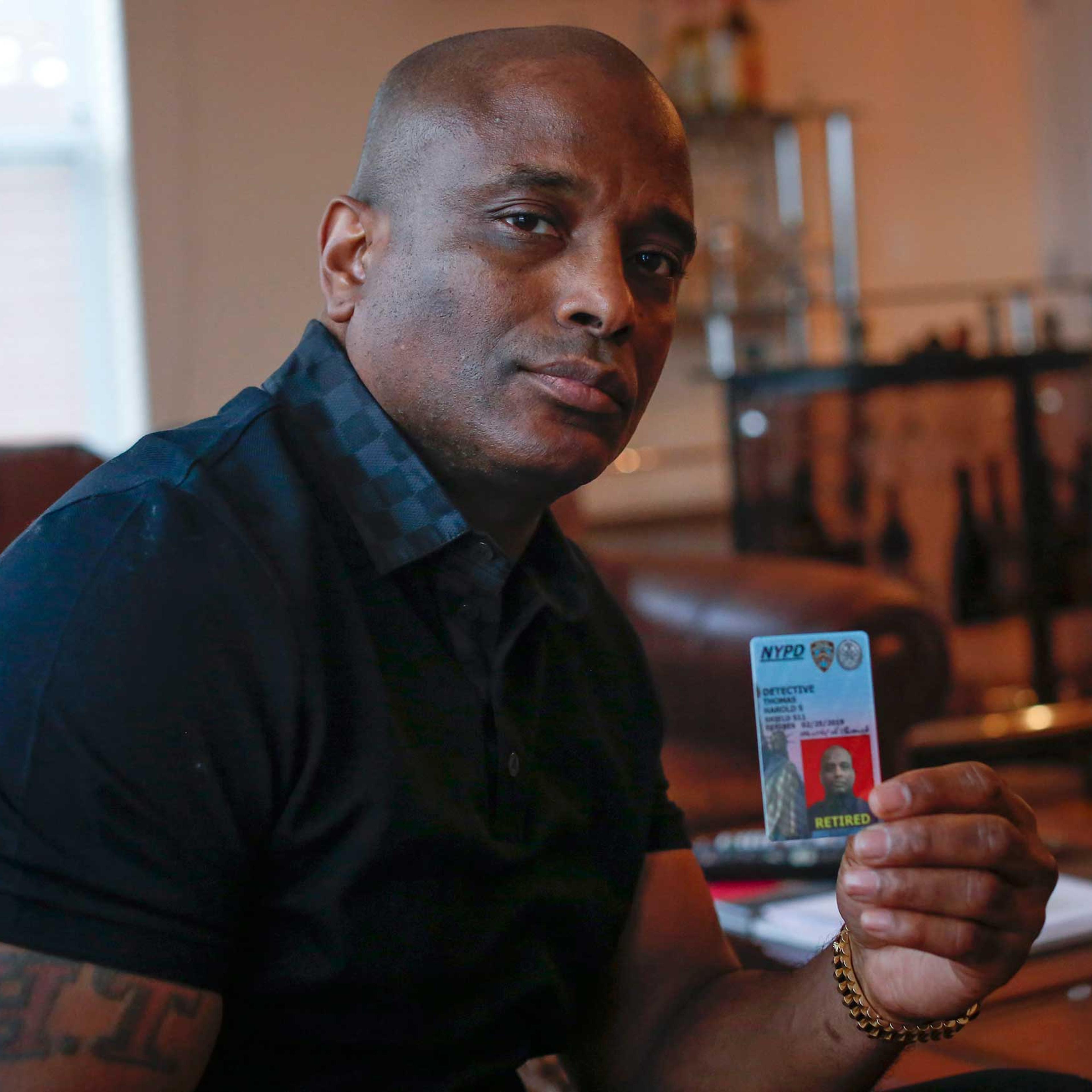 Retired NYPD detective Harold Thomas poses with his retired NYPD identification card in West Hempstead, New York