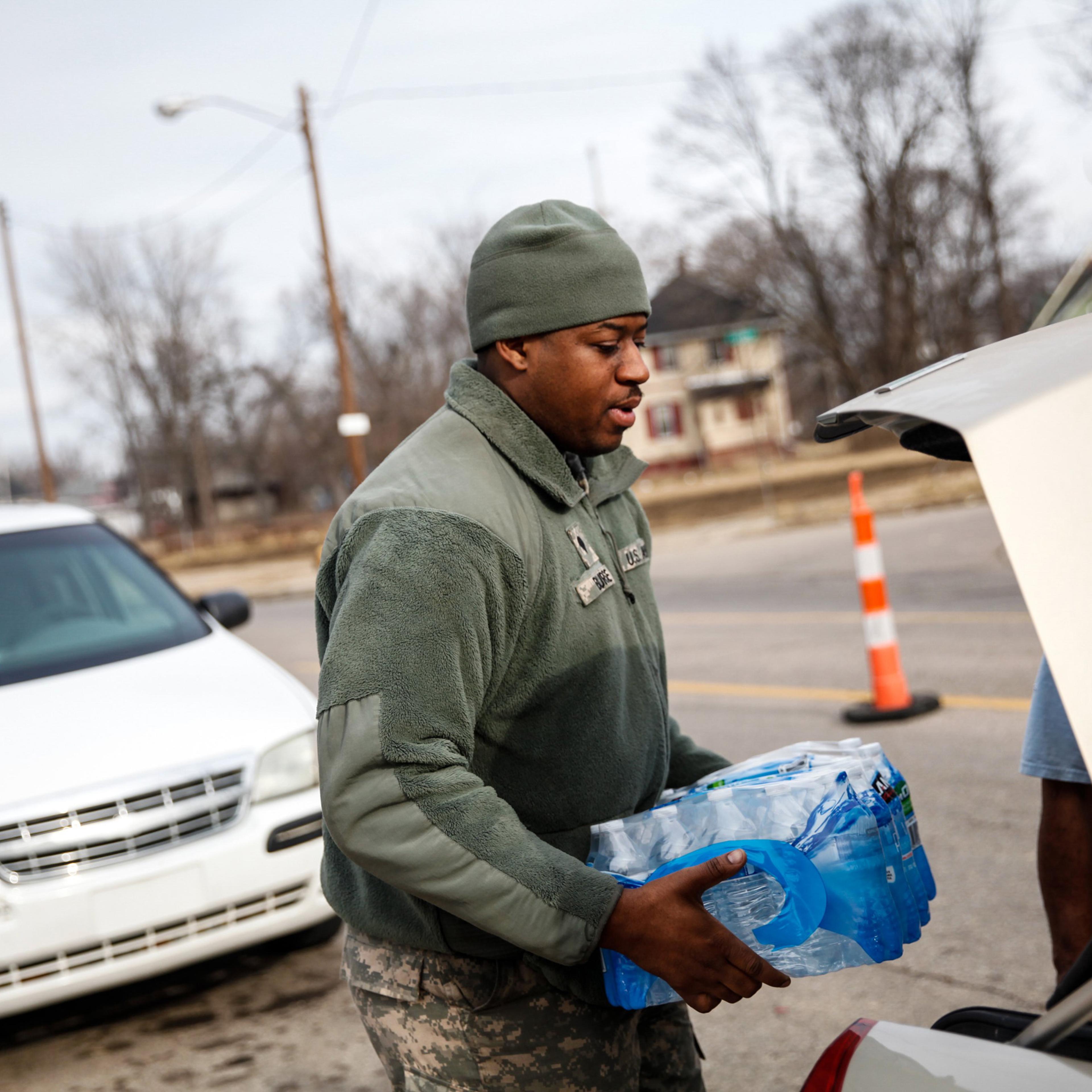 FLINT, MI - FEBRUARY 7: Army National Guard Spc. Terence Burse carries bottled water out to the car for a resident on February 7, 2016 in Flint, Michigan. Months ago the city told citizens they could use tap water if they boiled it first, but now say it