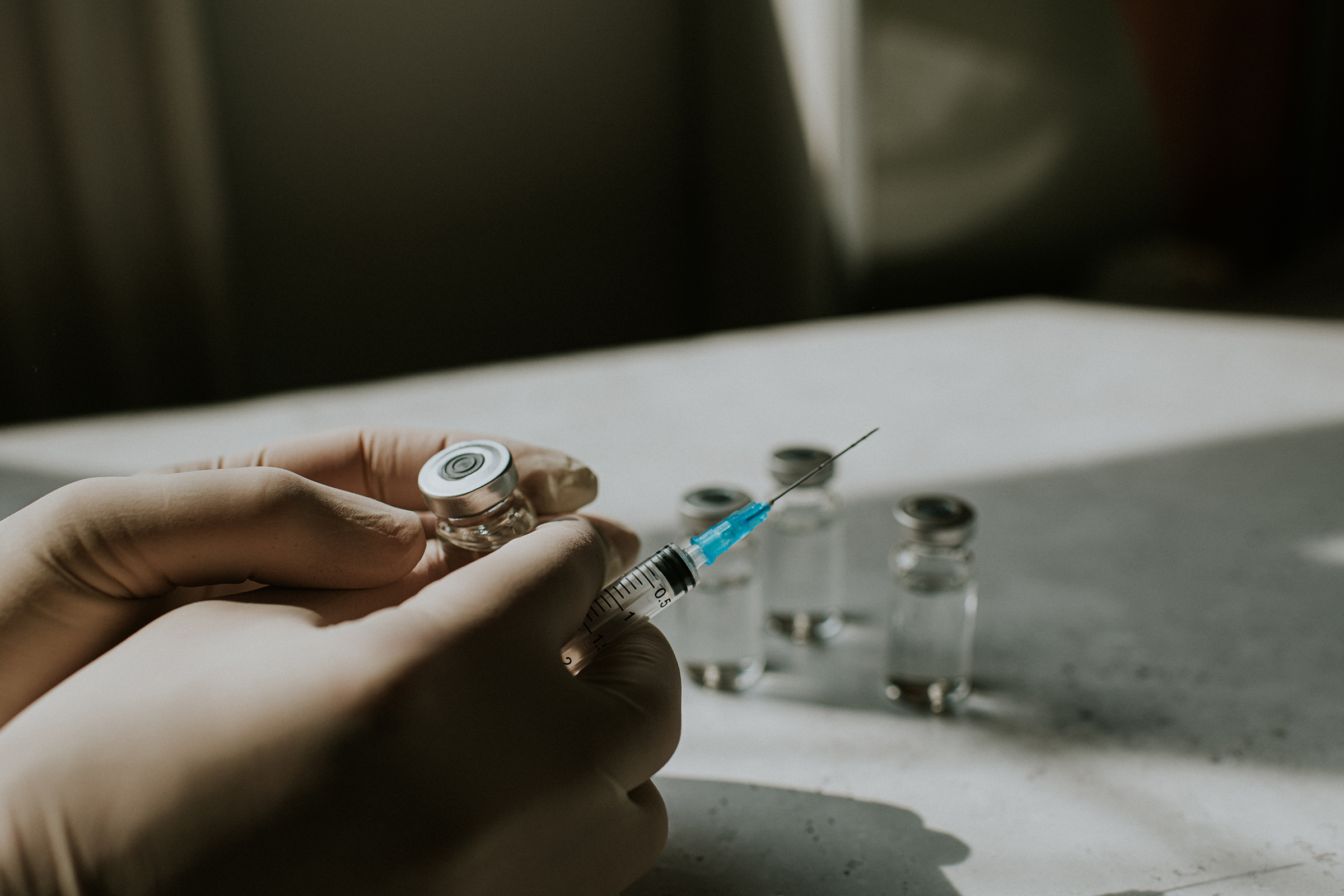Gloved hand holds a syringe and a vial