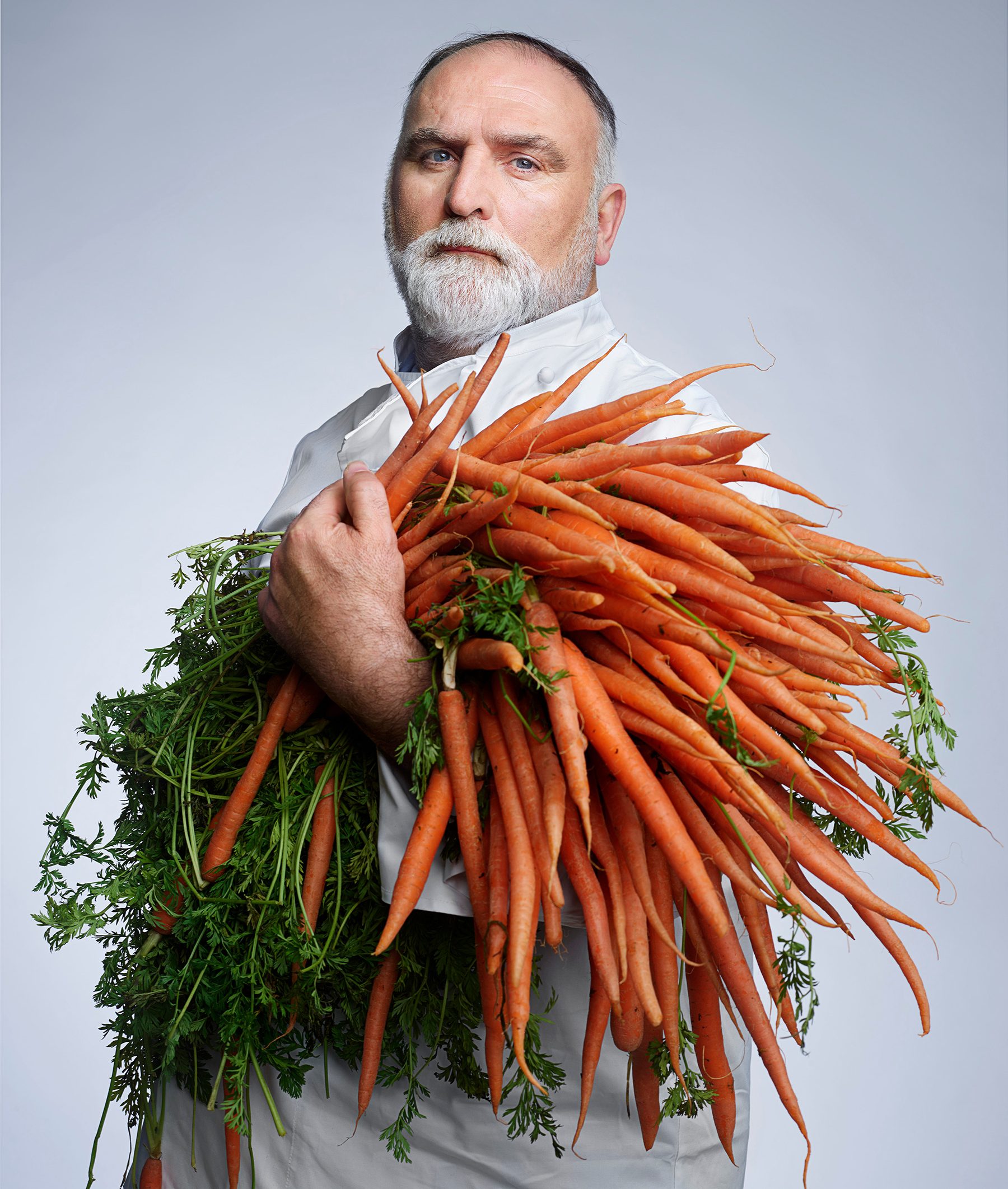 Chef José Andrés poses for a portrait while holding a large bundle of carrots