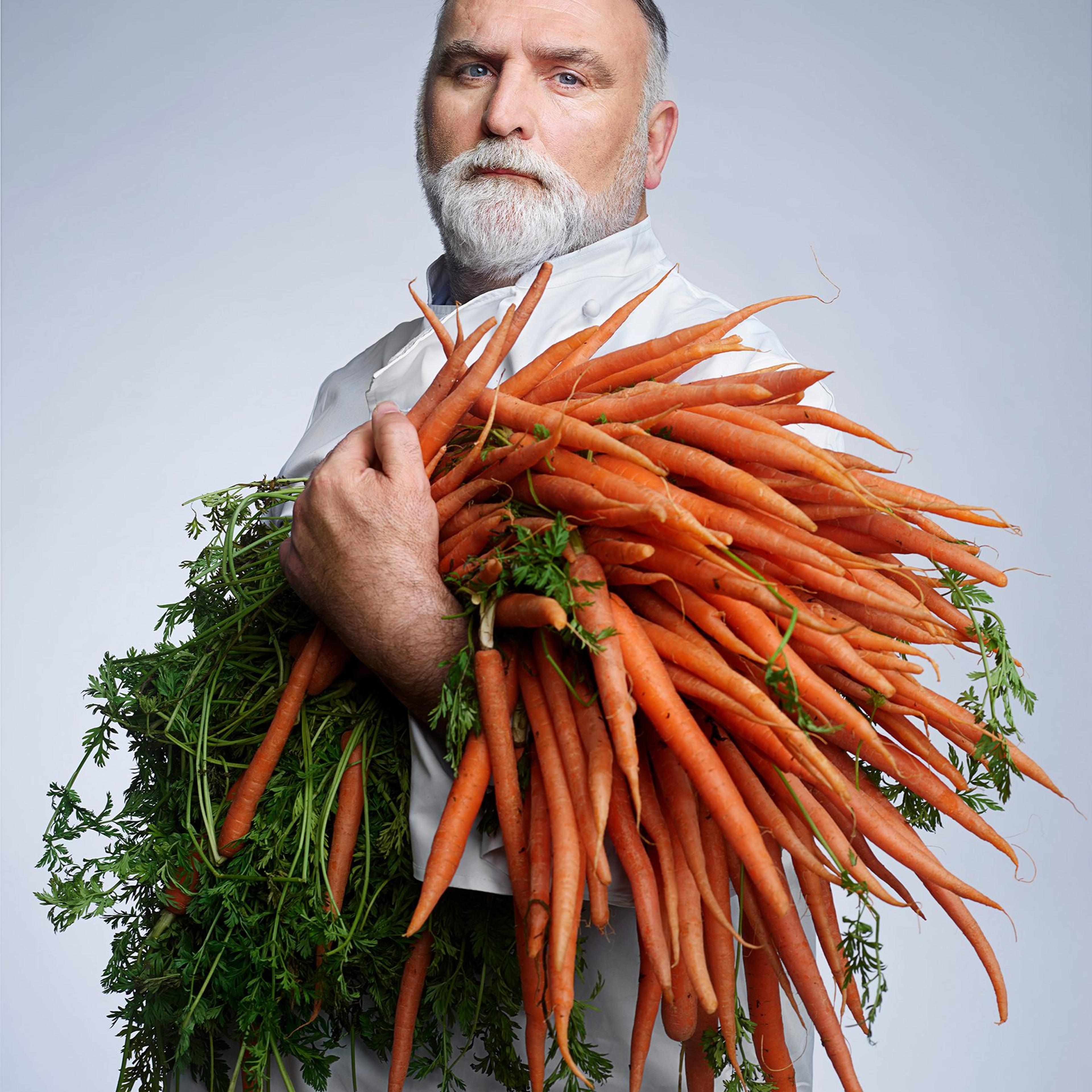 Chef José Andrés poses for a portrait while holding a large bundle of carrots
