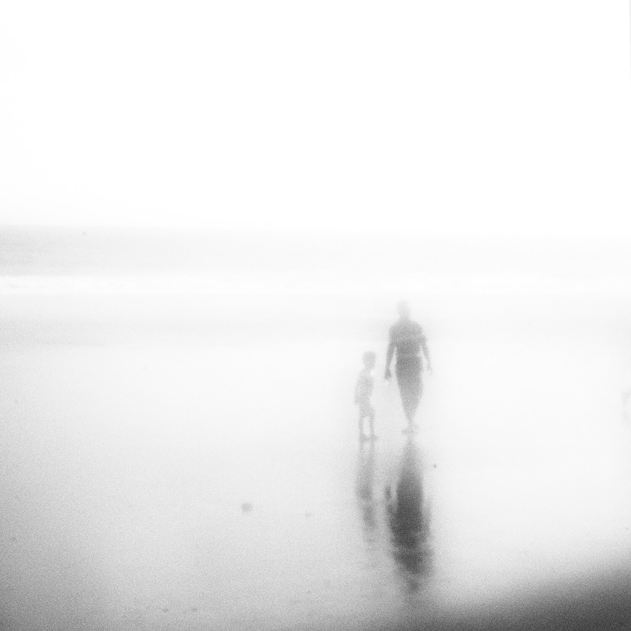 Silhouette Father And Son On Beach In Foggy Weather