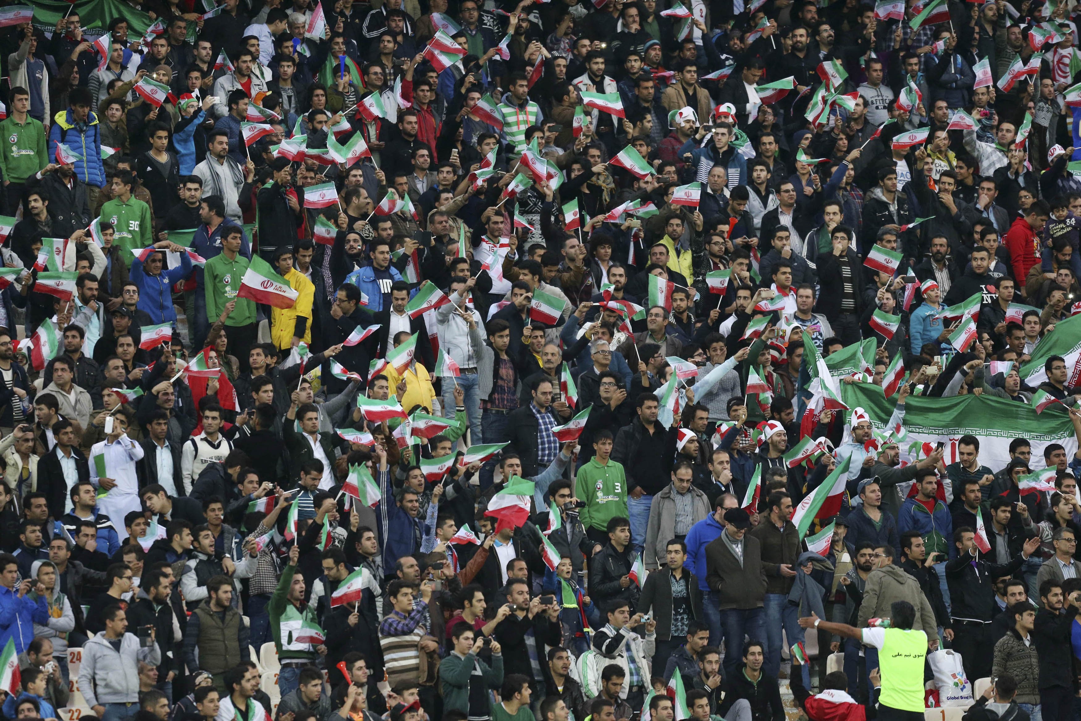 Iranian soccer supporters wave their country's flag following a friendly match at the Azadi, (freedom) stadium in Tehran, Iran on Nov. 18, 2014.