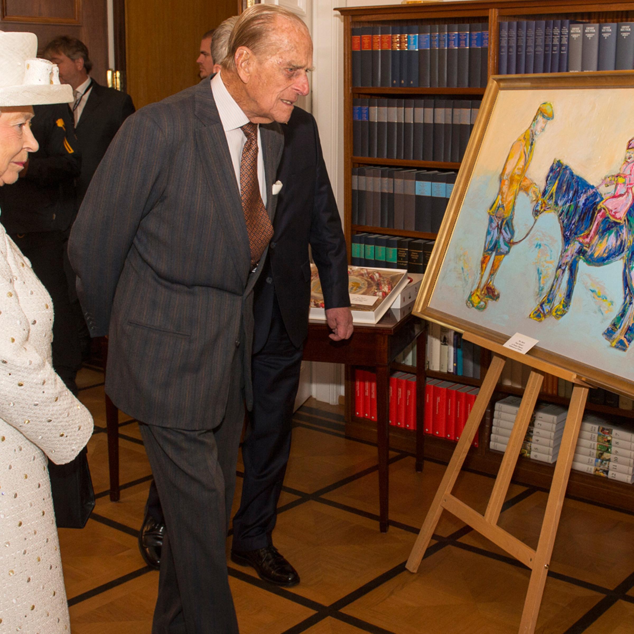 Britain's Queen Elizabeth and Prince Philip look at a painting presented to her during a visit to Germany's President's official residence, in Berlin, Germany, June 24, 2015.