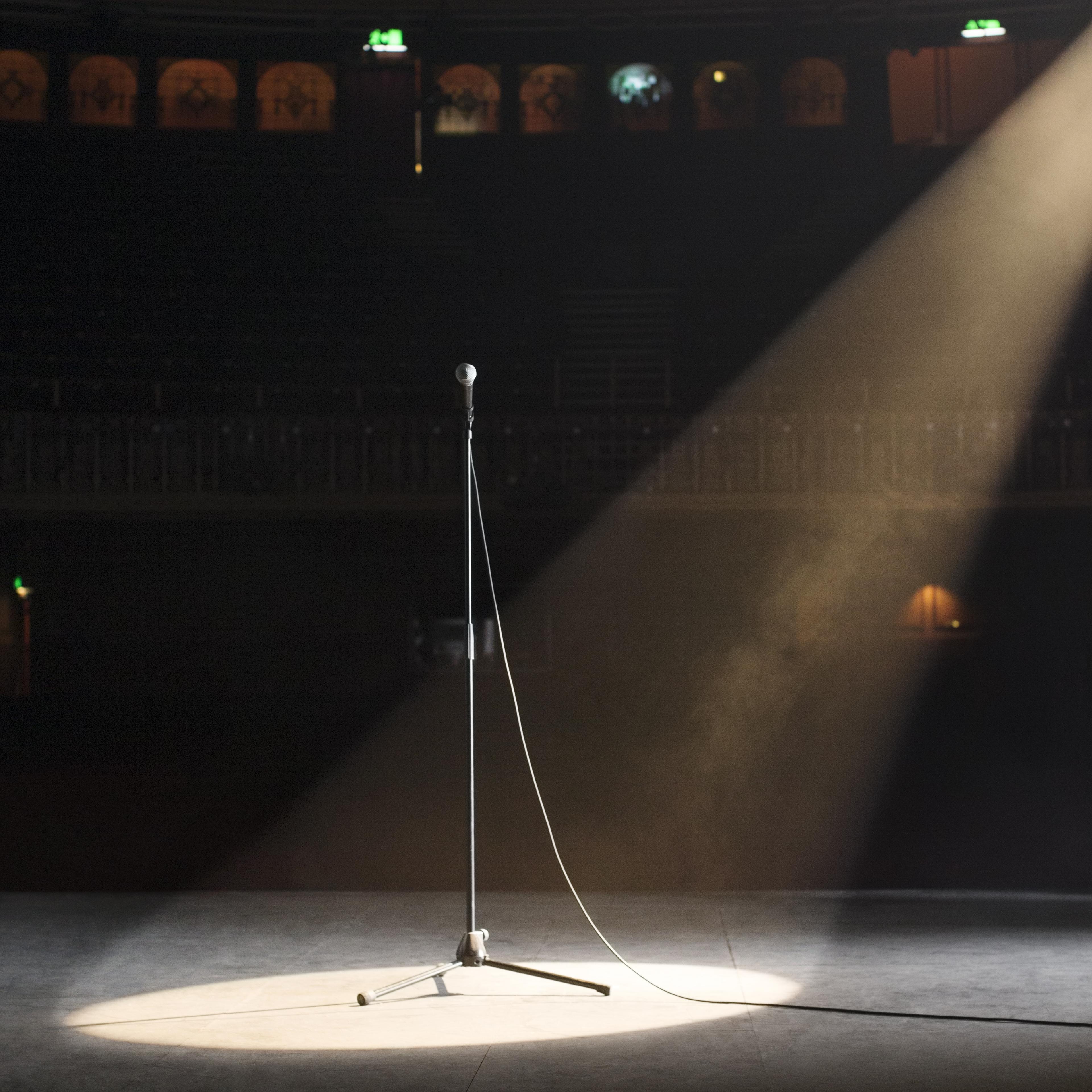 Microphone in spotlight on empty theater stage