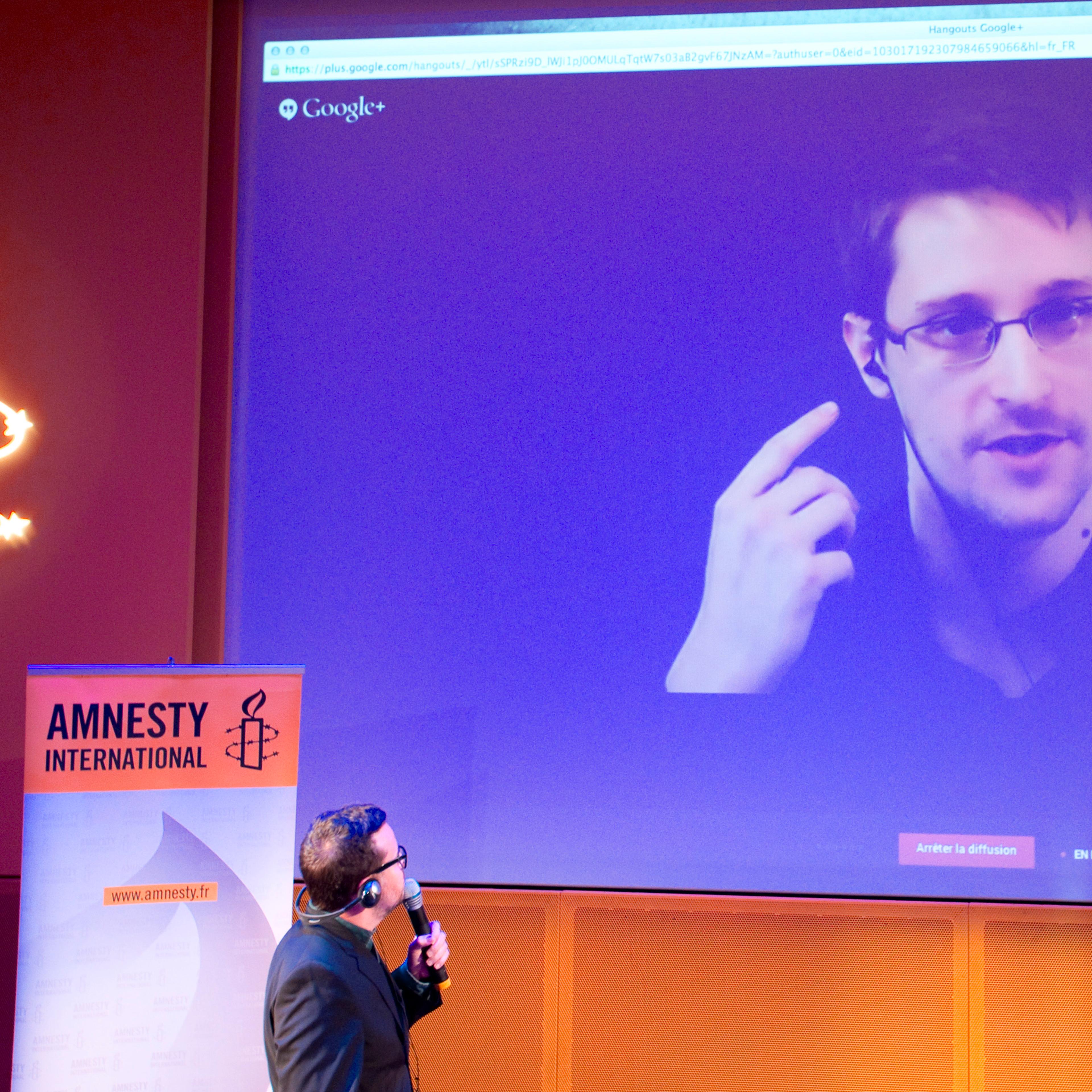 Former US National Security Agency contractor Edward Snowden, who is in Moscow, is seen on a giant screen during a live video conference for an interview as part of Amnesty International's annual Write for Rights campaign at the Gaite Lyrique in Paris