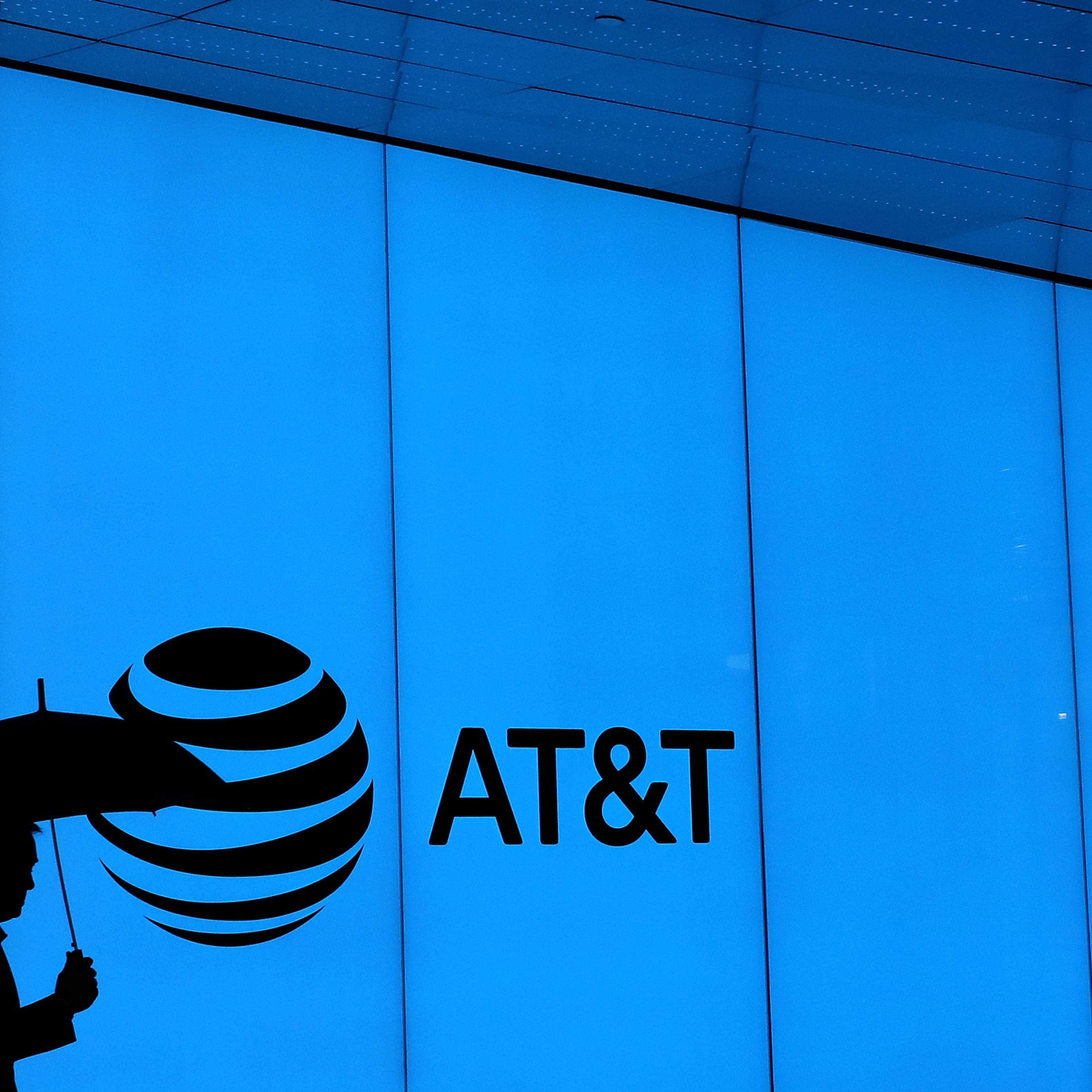 silhouette of a man holding umbrella against blue wall with AT&T logo