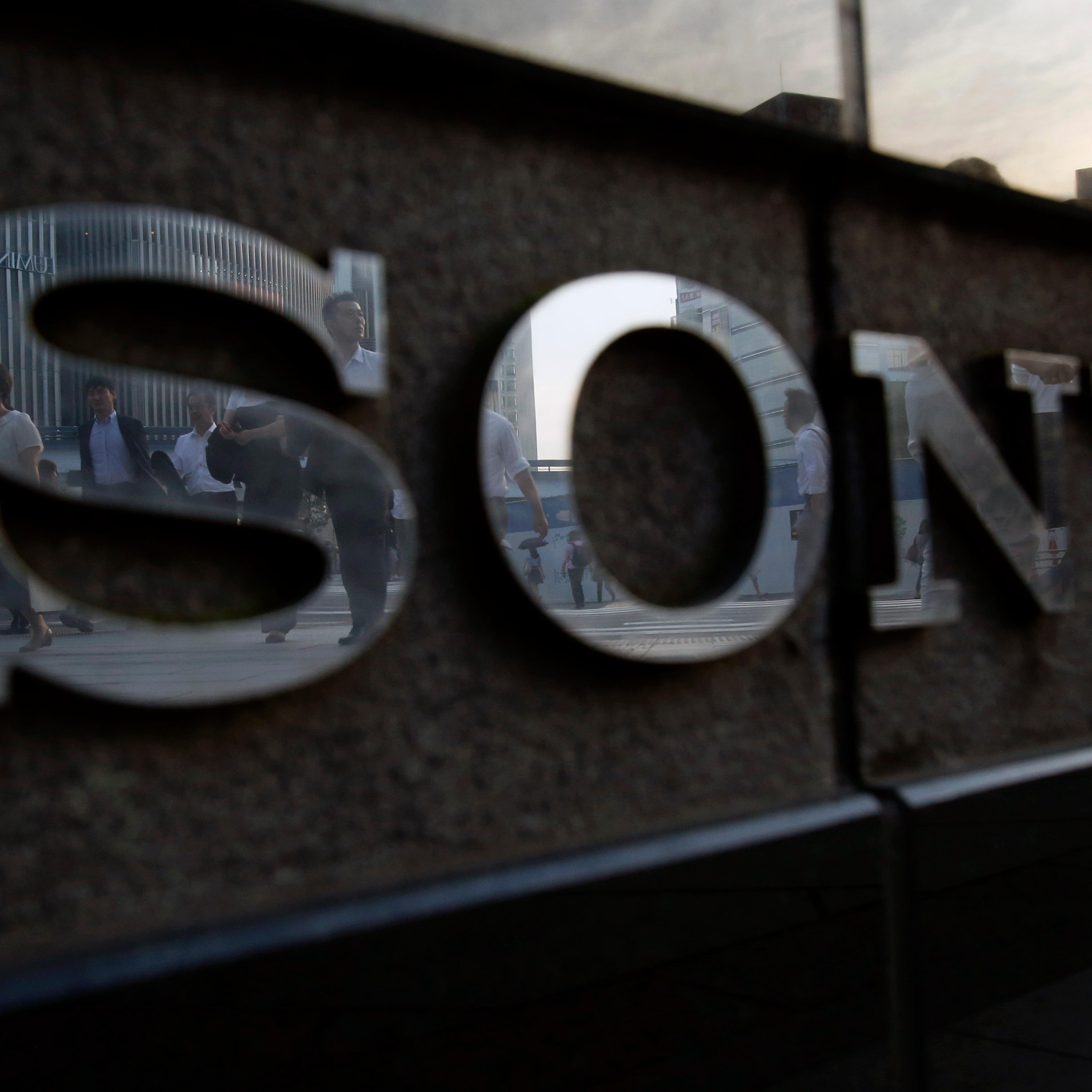 Pedestrians are reflected in a logo of Sony Corp outside its showroom in Tokyo