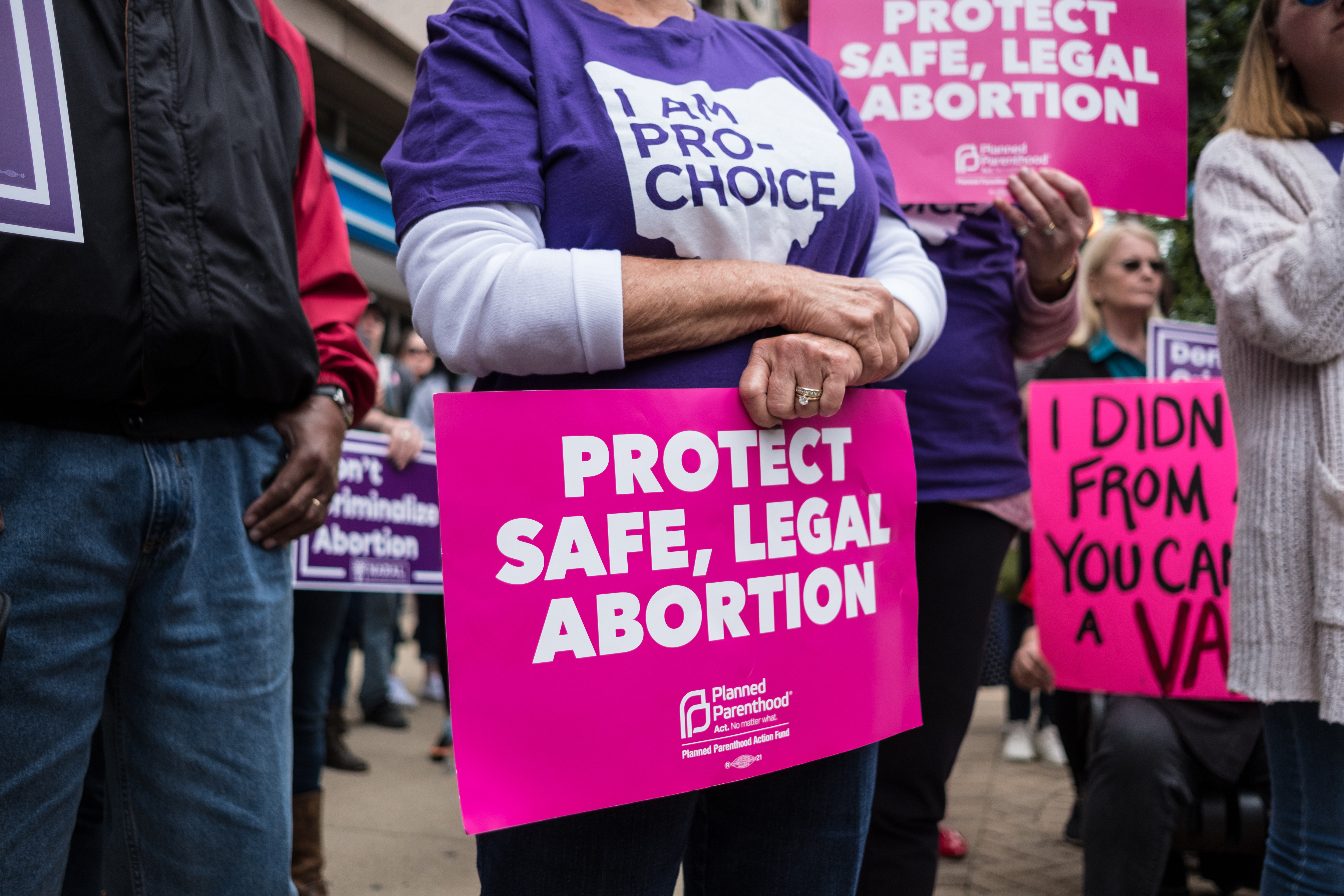 An activist seen holding a placard that says protect safe,