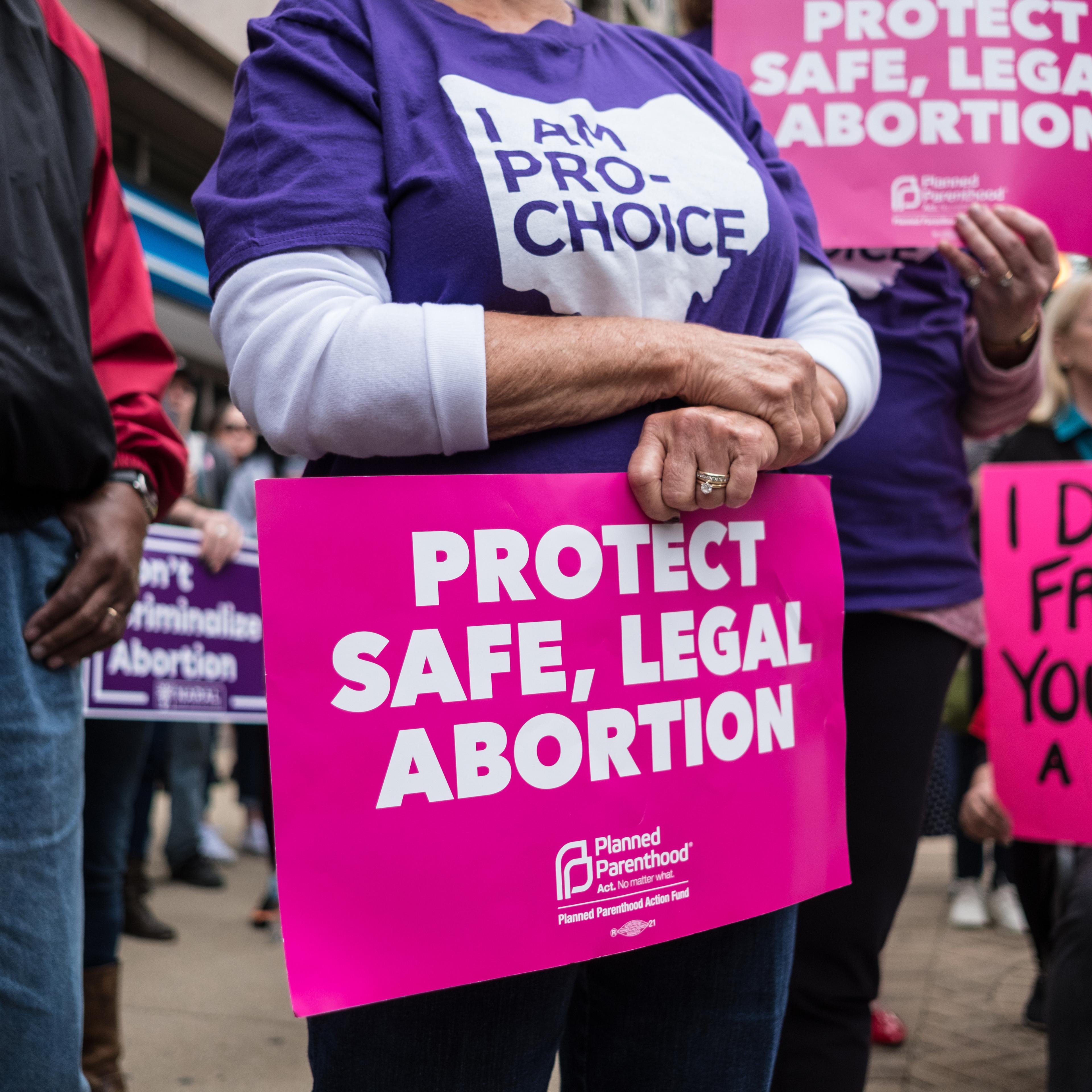An activist seen holding a placard that says protect safe,