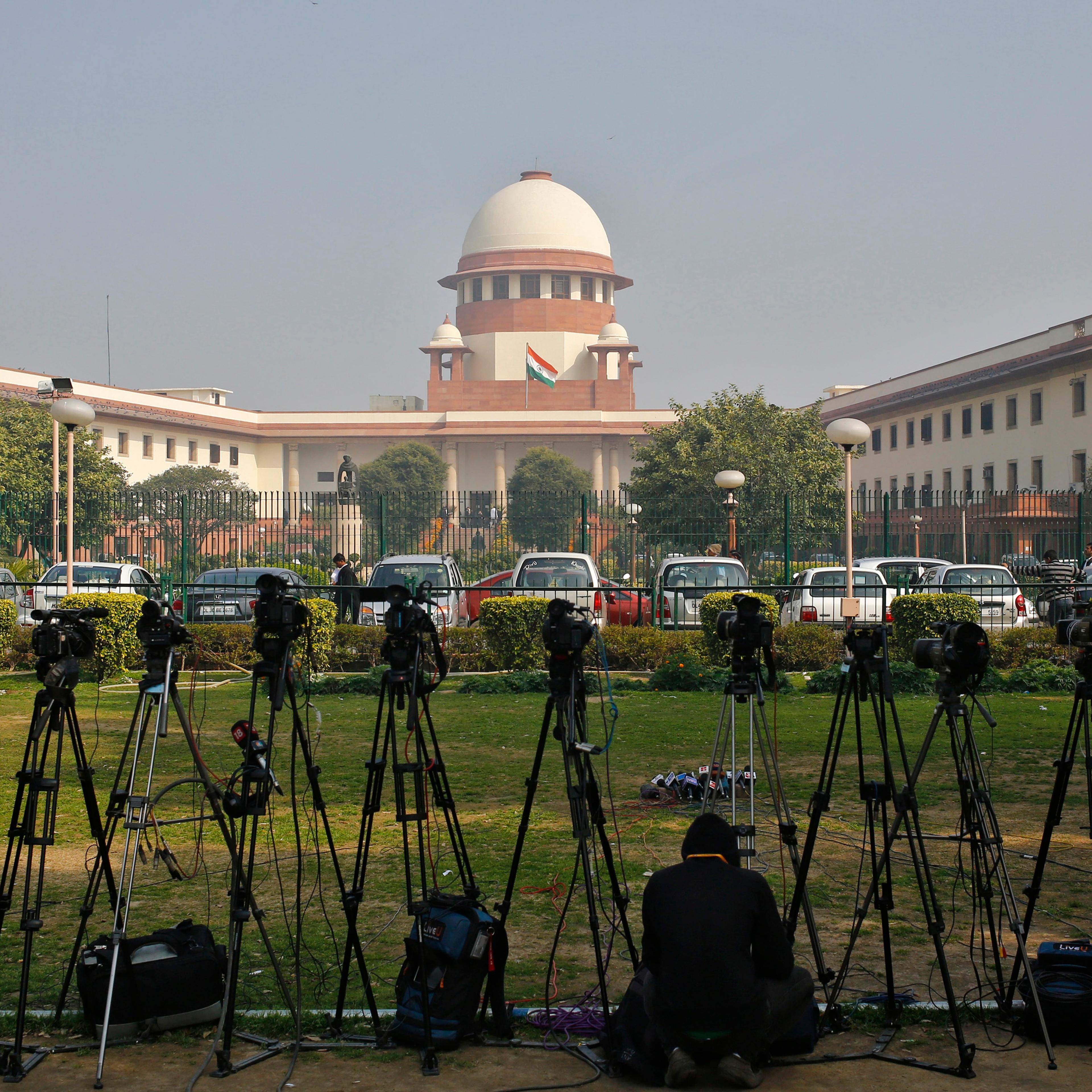 A television journalist sets his camera inside the premises of the Supreme Court in New Delhi