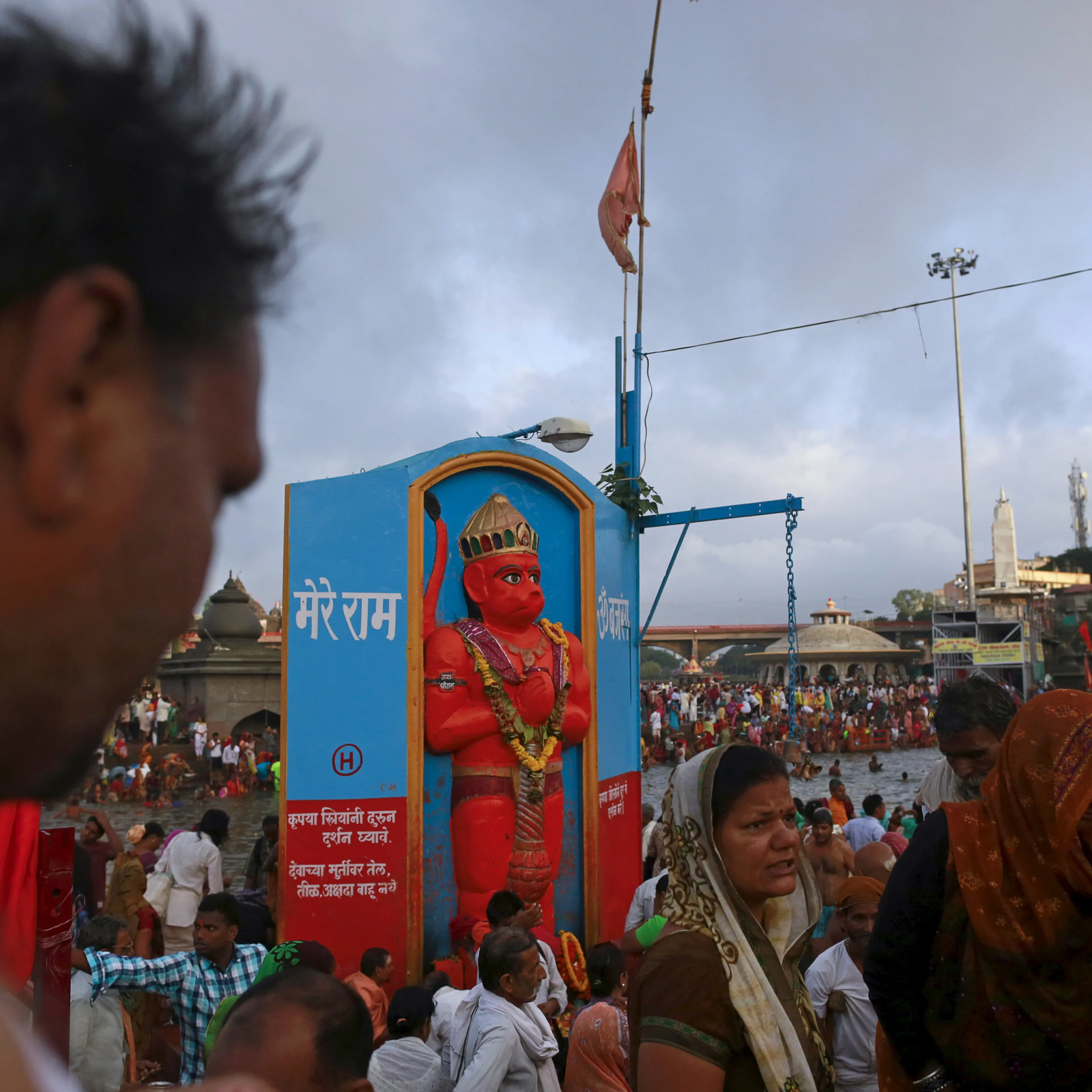 Devotees walk past an Hanuman idol on the banks of Godavari river during "Kumbh Mela" or the Pitcher Festival in Nashik