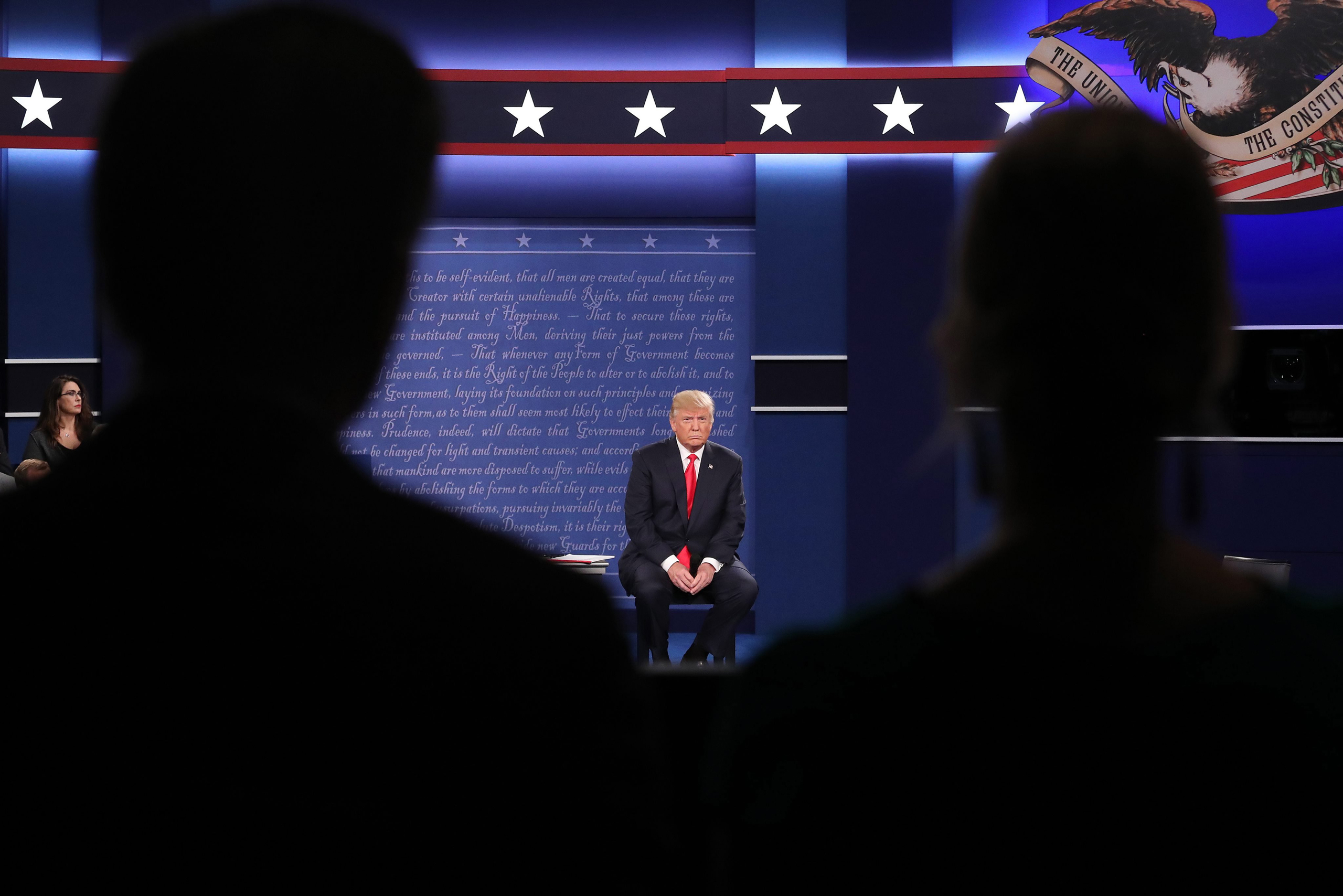 epa05579016 Republican Donald Trump (L) sits in his chair as Democrat Hillary Clinton speaks during the second Presidential Debate at Washington University in St. Louis, Missouri, USA, 09 October 2016. The third and final debate will be held 19 October i