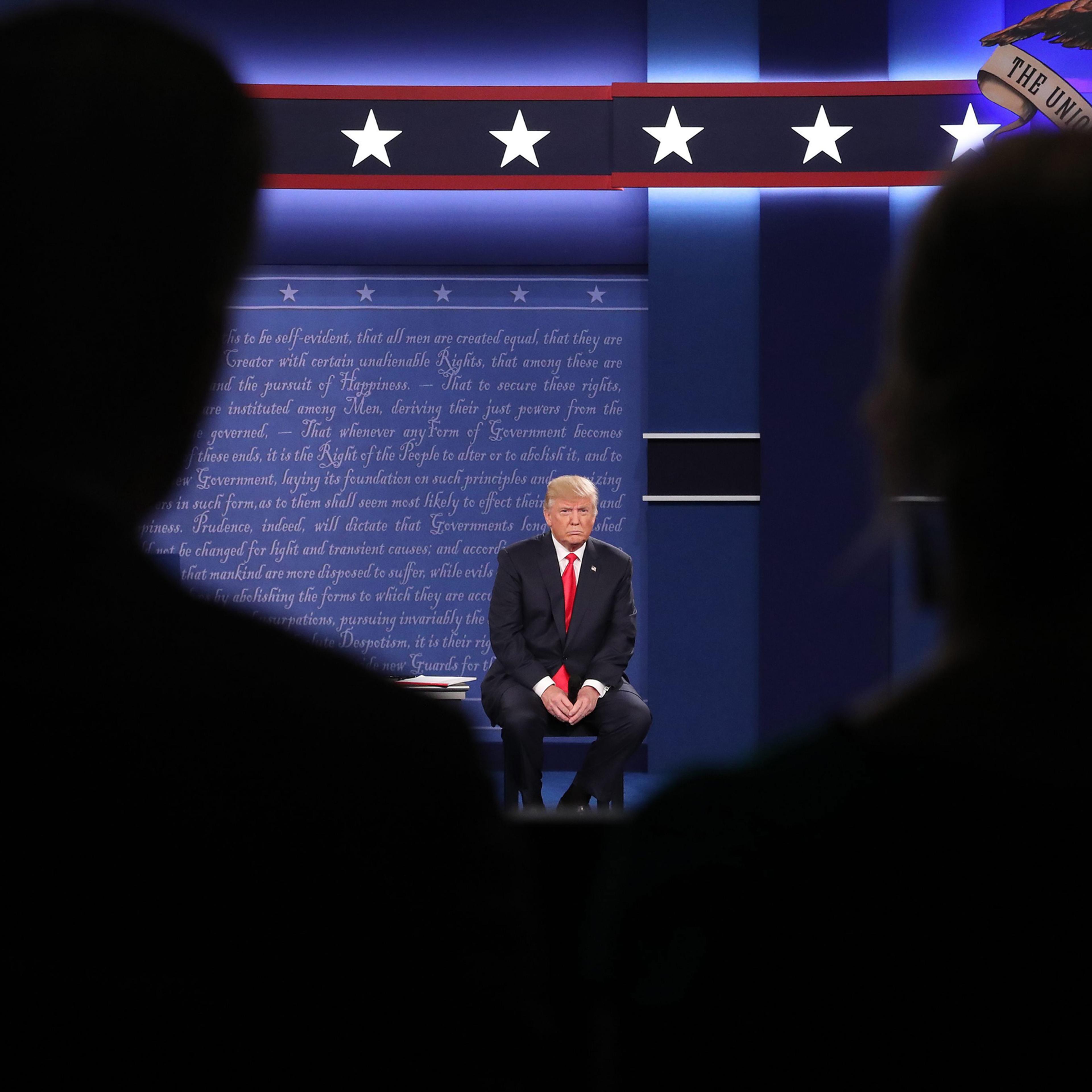epa05579016 Republican Donald Trump (L) sits in his chair as Democrat Hillary Clinton speaks during the second Presidential Debate at Washington University in St. Louis, Missouri, USA, 09 October 2016. The third and final debate will be held 19 October i