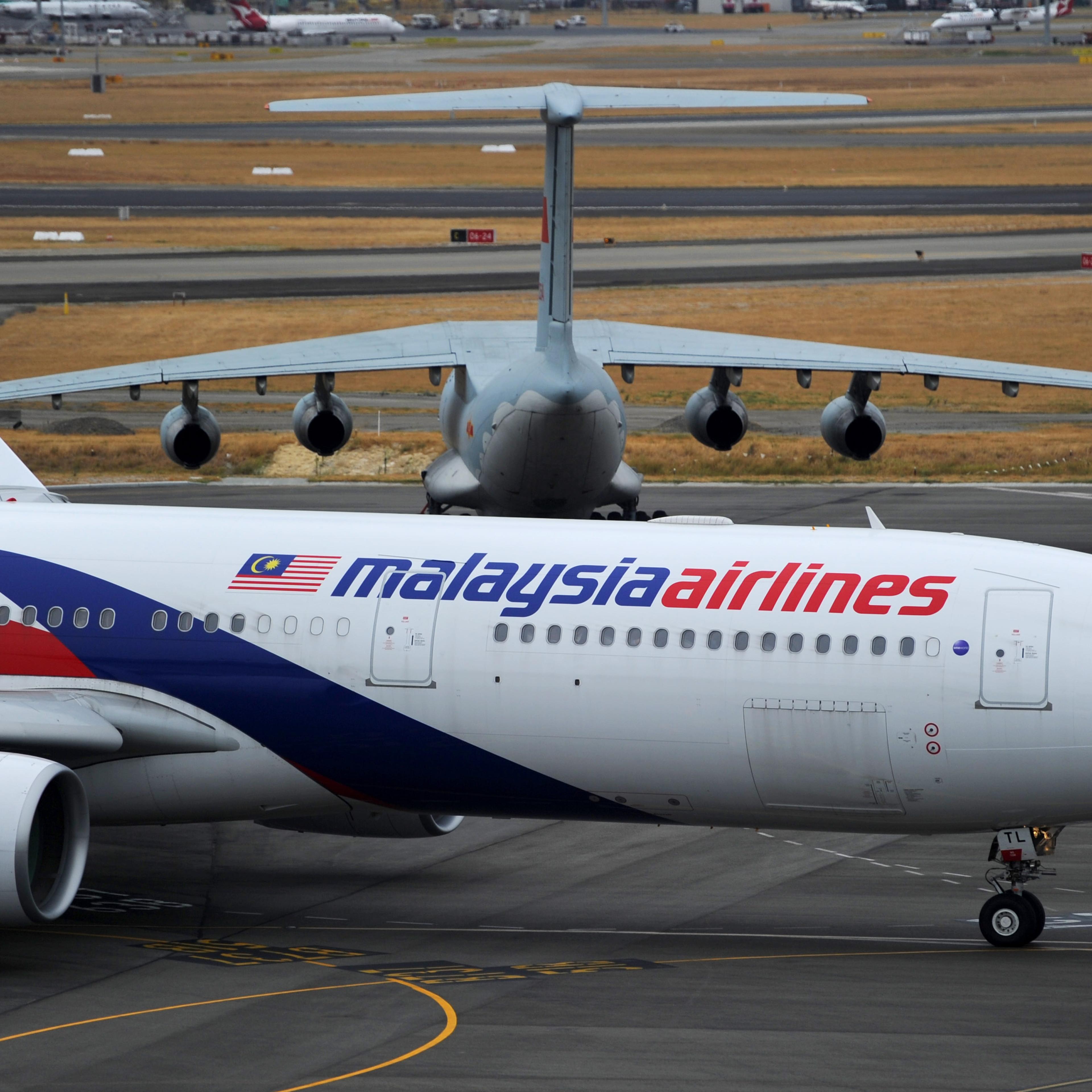 A Malaysia Airlines plane prepares to go out onto the runway and passes by a stationary Chinese Ilyushin 76 aircraft (top) at Perth International Airport on March 25, 2014 in Perth, Australia.