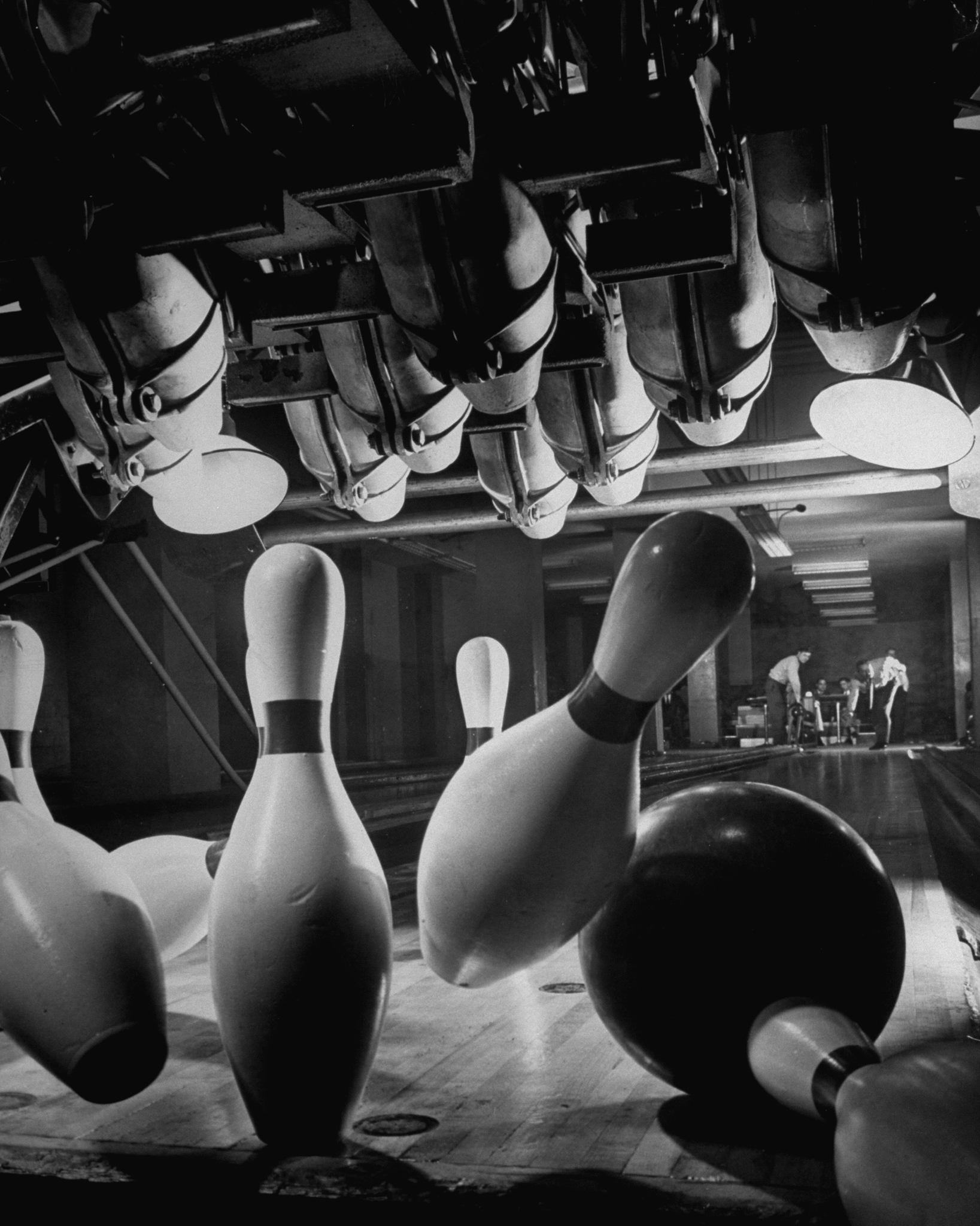 Pins scatter as they fall after being struck by a bowling ball