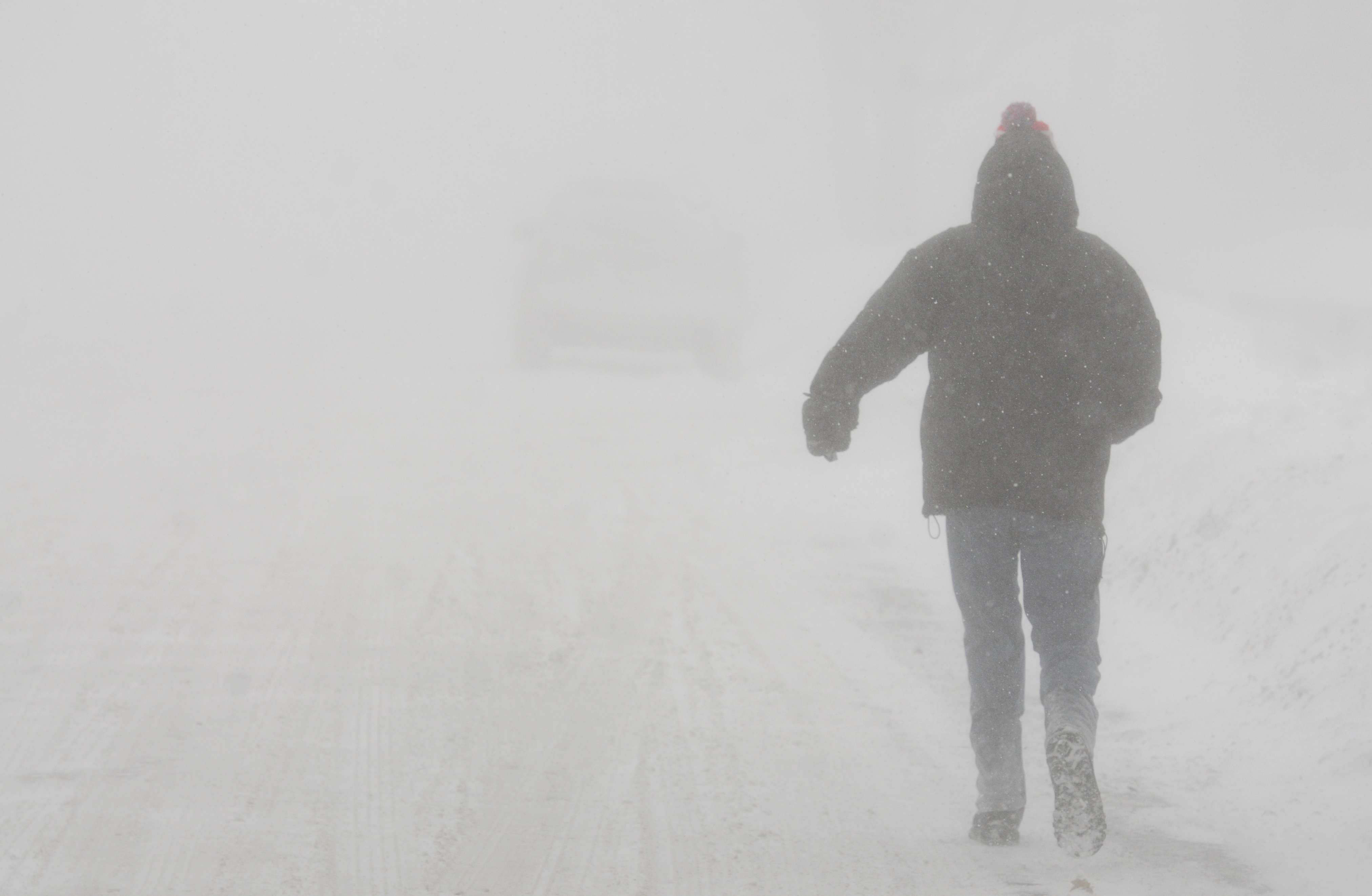 A pedestrian walks down State Street in St. Joseph, Mich., in whiteout conditions, Saturday, February 14, 2015.  All regions of Michigan were under some winter weather emergency, warning or advisory on Saturday, and conditions included blizzards in the U