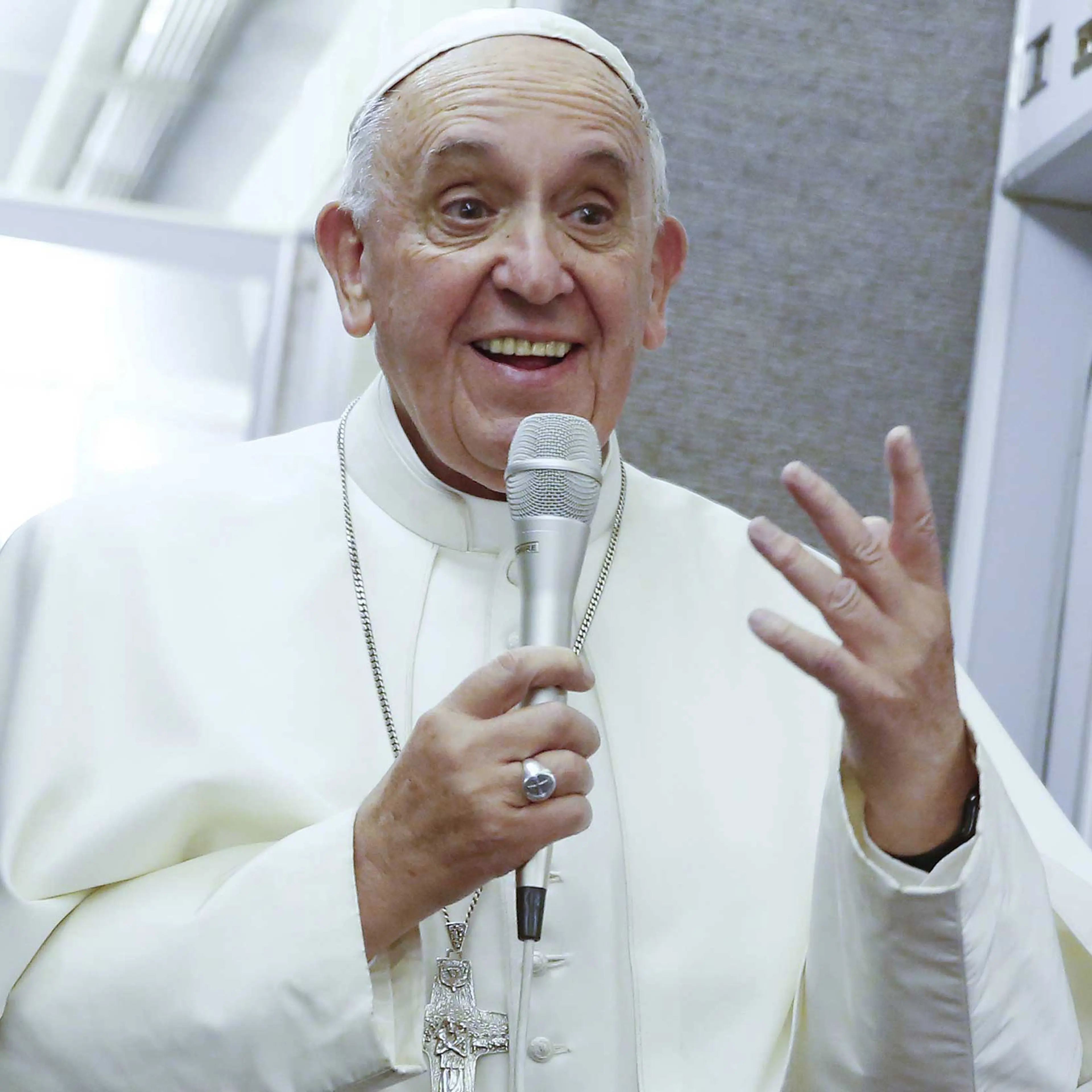 Pope Francis talks aboard the papal plane while en route to Italy