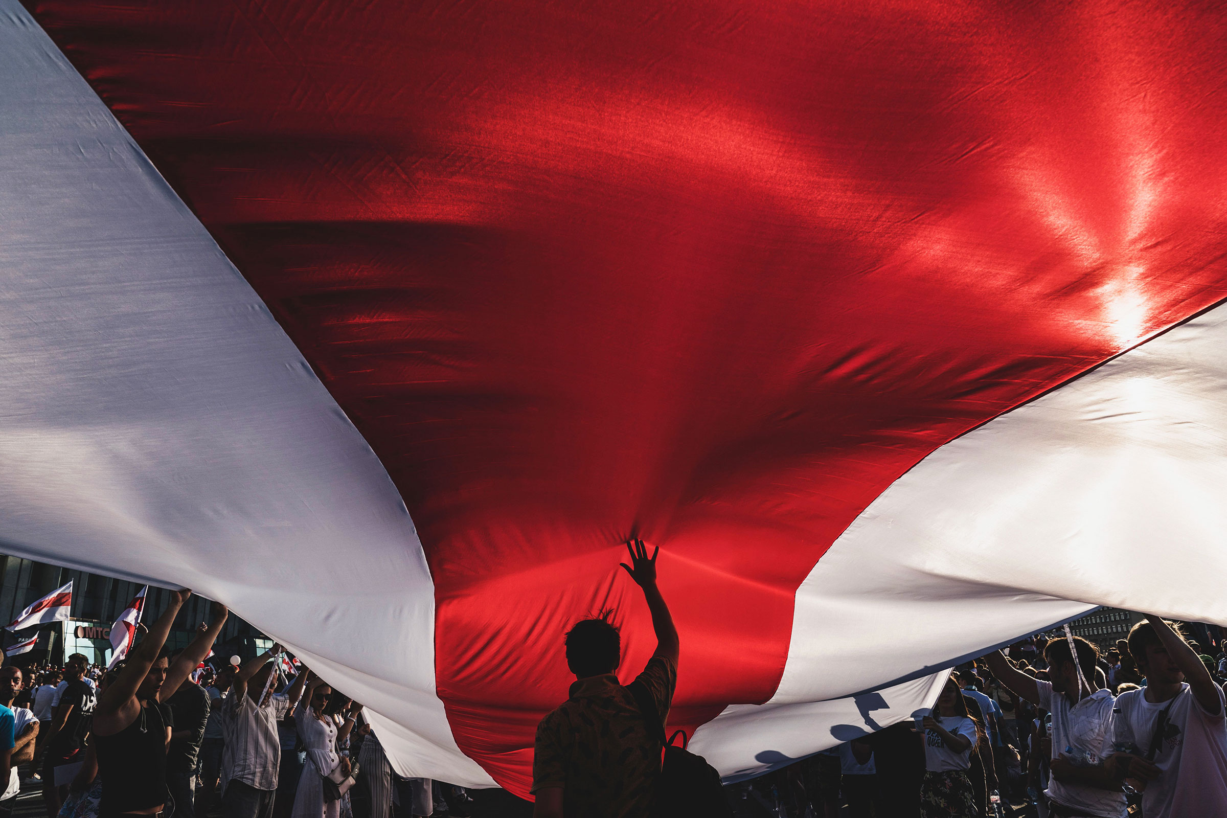 Protesters unfurl a banner in the colors of the former Belarus national flag as they call for the resignation of President Alexander Lukashenko in Minsk