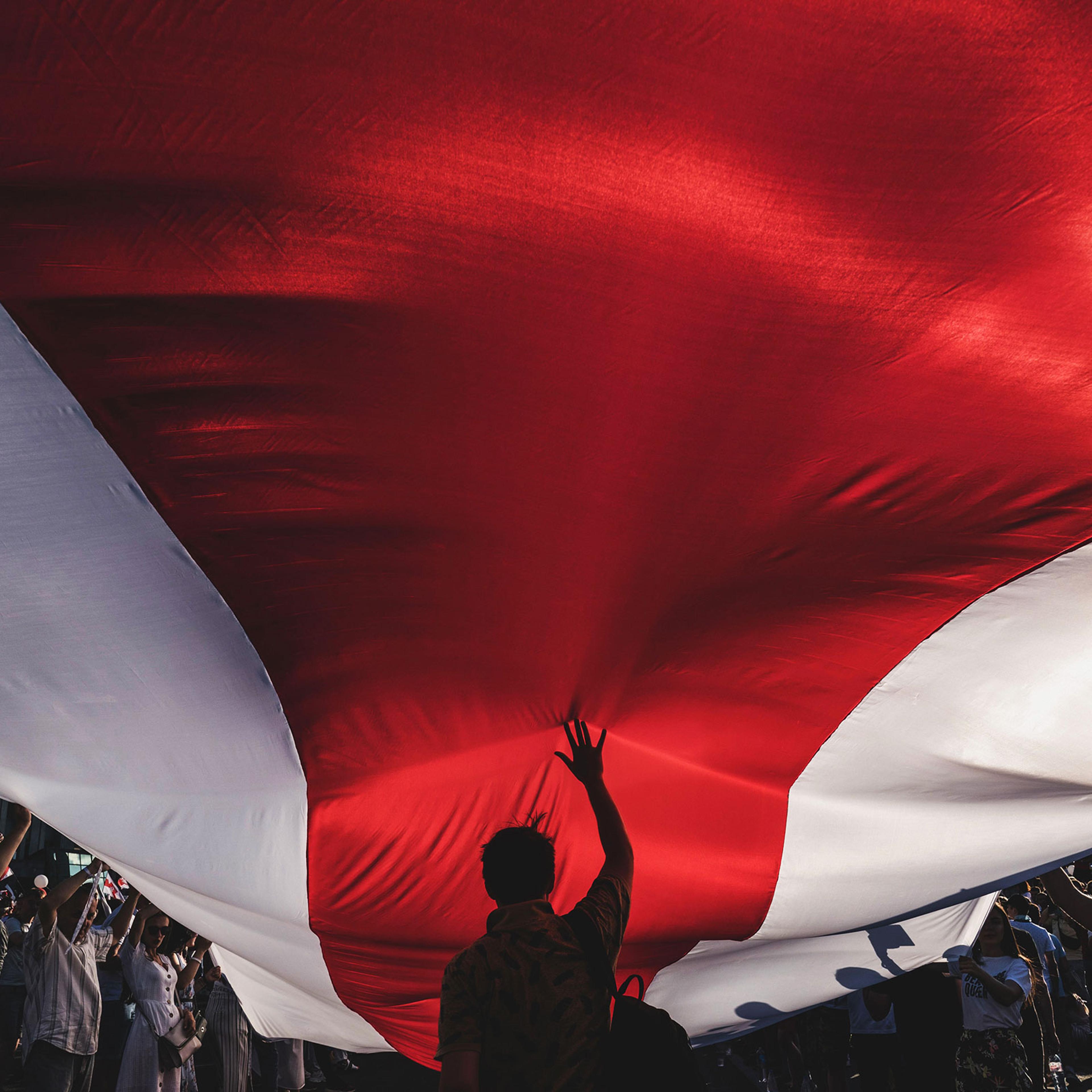 Protesters unfurl a banner in the colors of the former Belarus national flag as they call for the resignation of President Alexander Lukashenko in Minsk