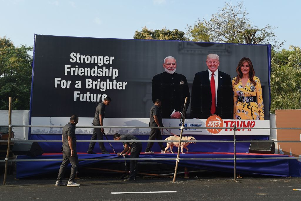 Gujarat police's bomb detection disposal squad officials along with a sniffer dog inspect a stage displaying pictures of India's Prime Minister Narendra Modi (L), US President Donald Trump (C) and First Lady Melania Trump (R), on the outskirts of Ahmedab