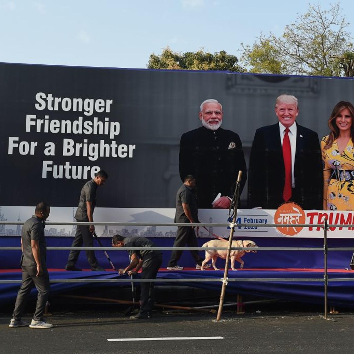 Gujarat police's bomb detection disposal squad officials along with a sniffer dog inspect a stage displaying pictures of India's Prime Minister Narendra Modi (L), US President Donald Trump (C) and First Lady Melania Trump (R), on the outskirts of Ahmedab