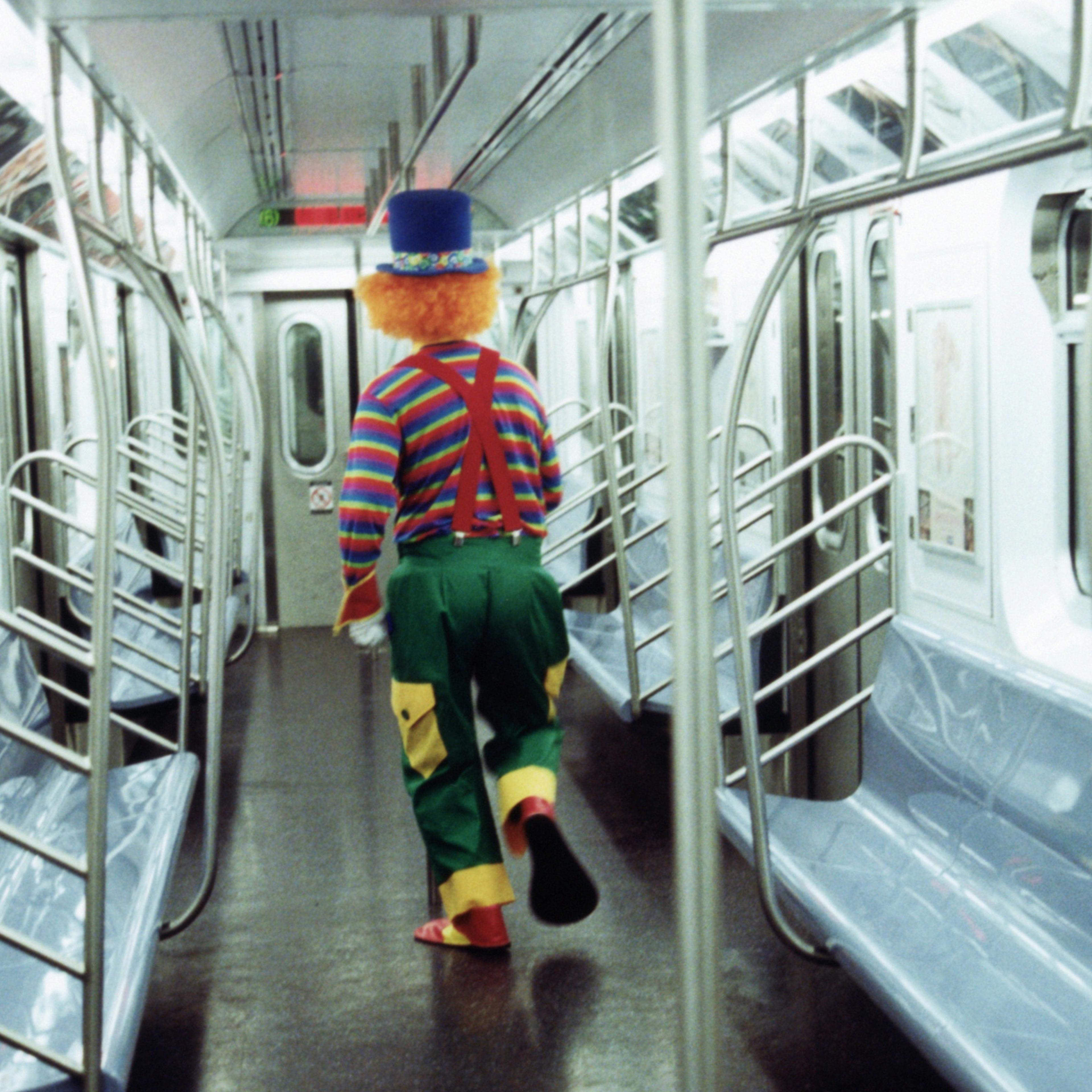 Clown walking through subway car, rear view