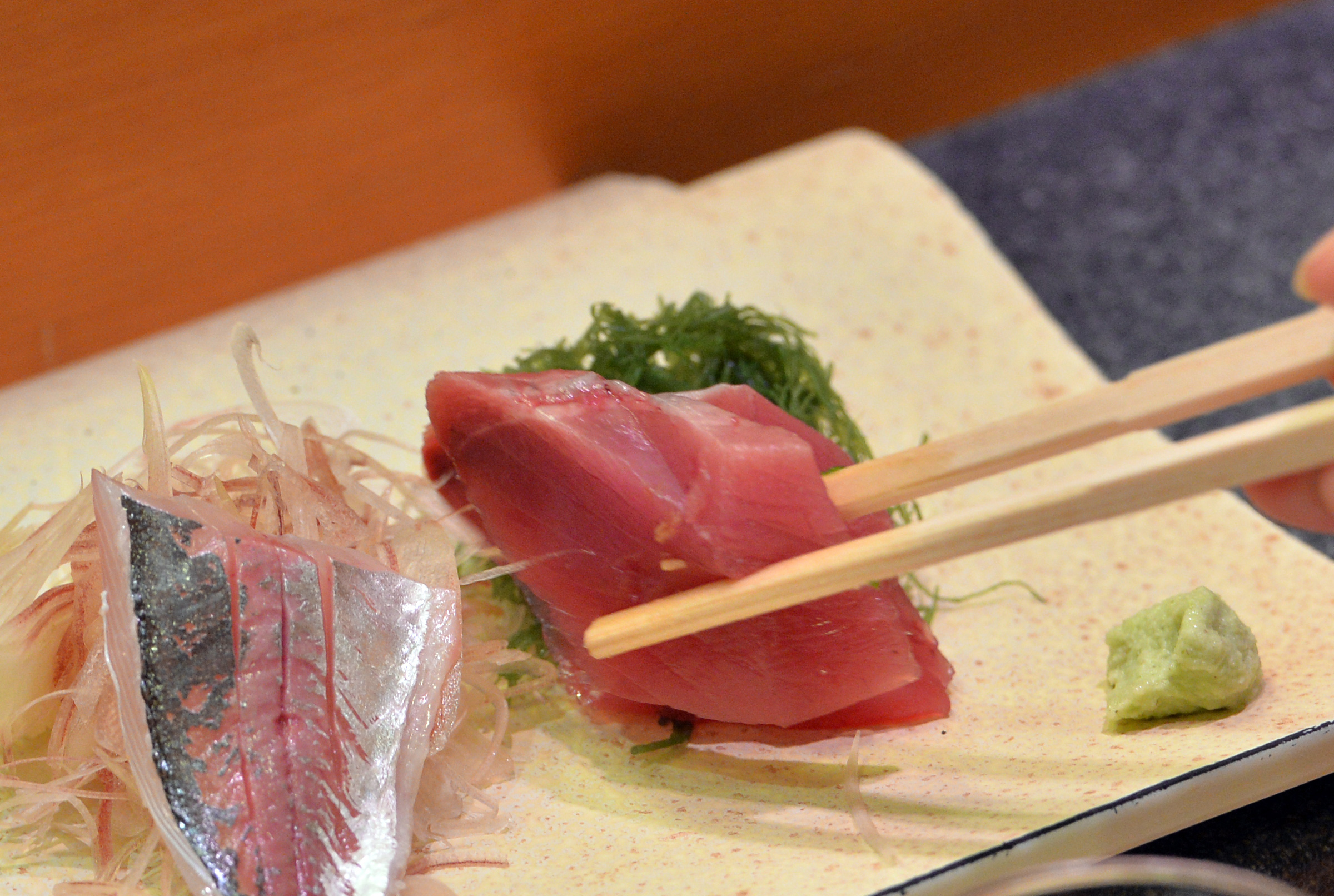 A customer eats bonito and horse mackerel sashimi (raw fish) at a high-end sushi restaurant in Tokyo on July 16, 2013.