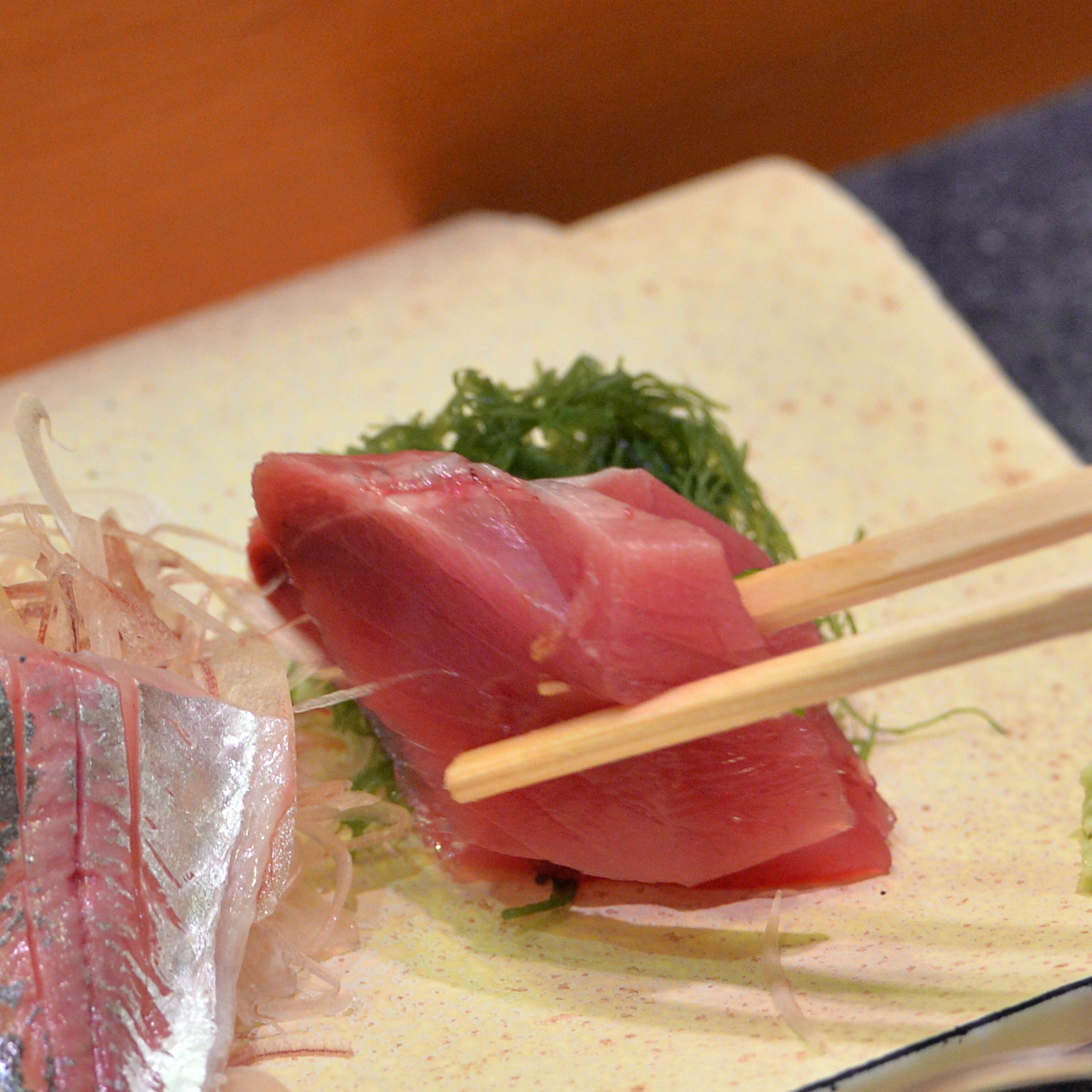 A customer eats bonito and horse mackerel sashimi (raw fish) at a high-end sushi restaurant in Tokyo on July 16, 2013.