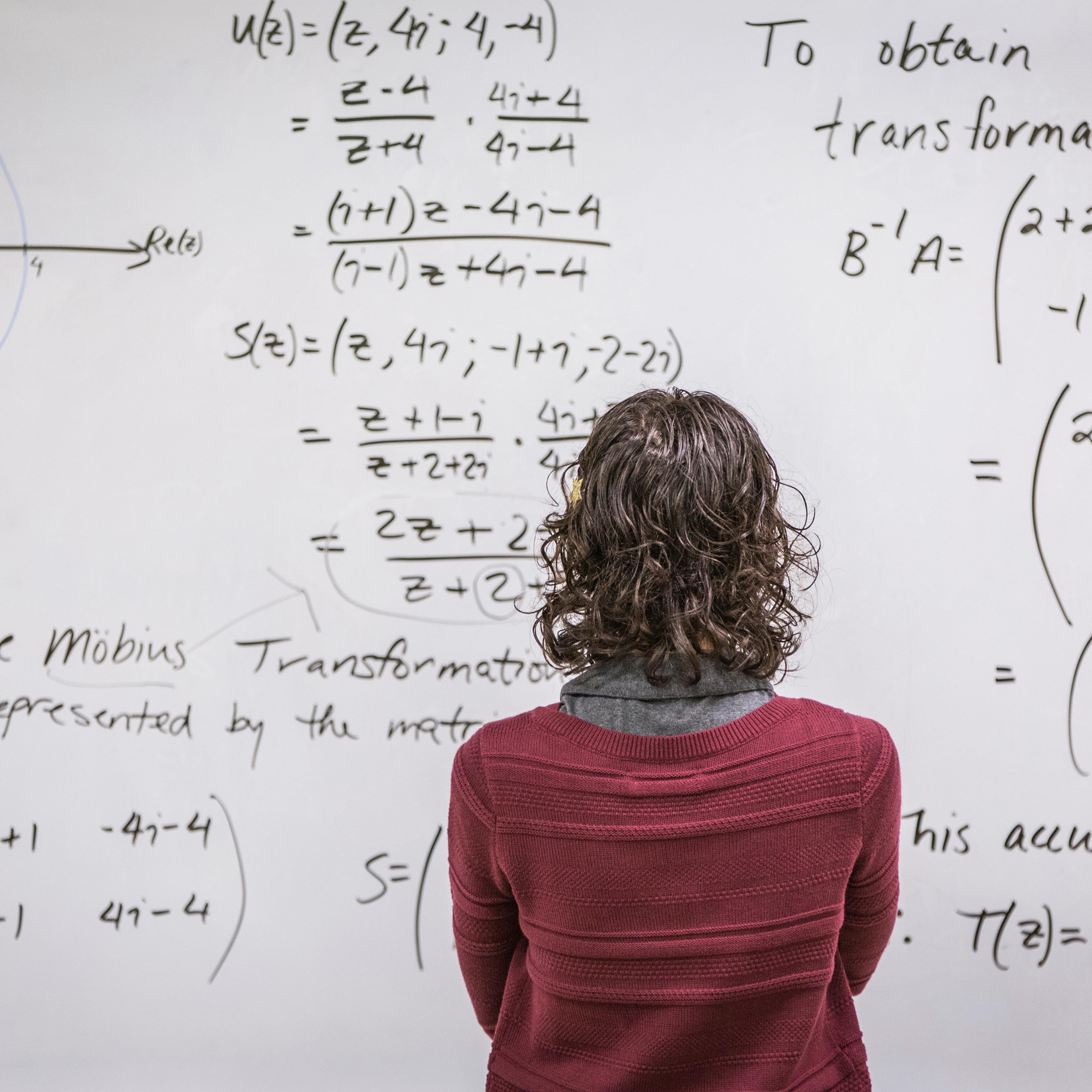 Caucasian professor examining equations on whiteboard