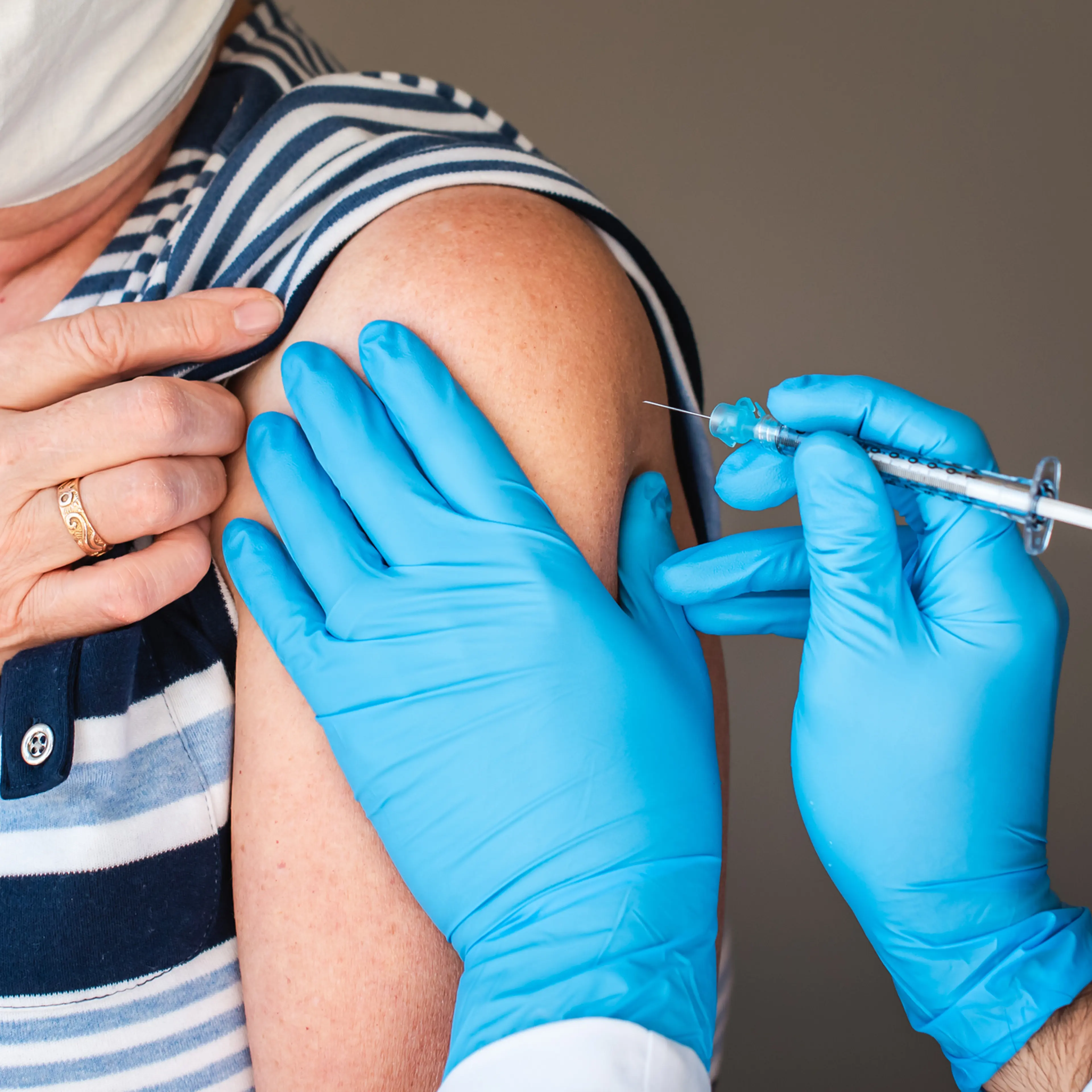 Close up of older woman getting injected with a vaccine in upper arm.