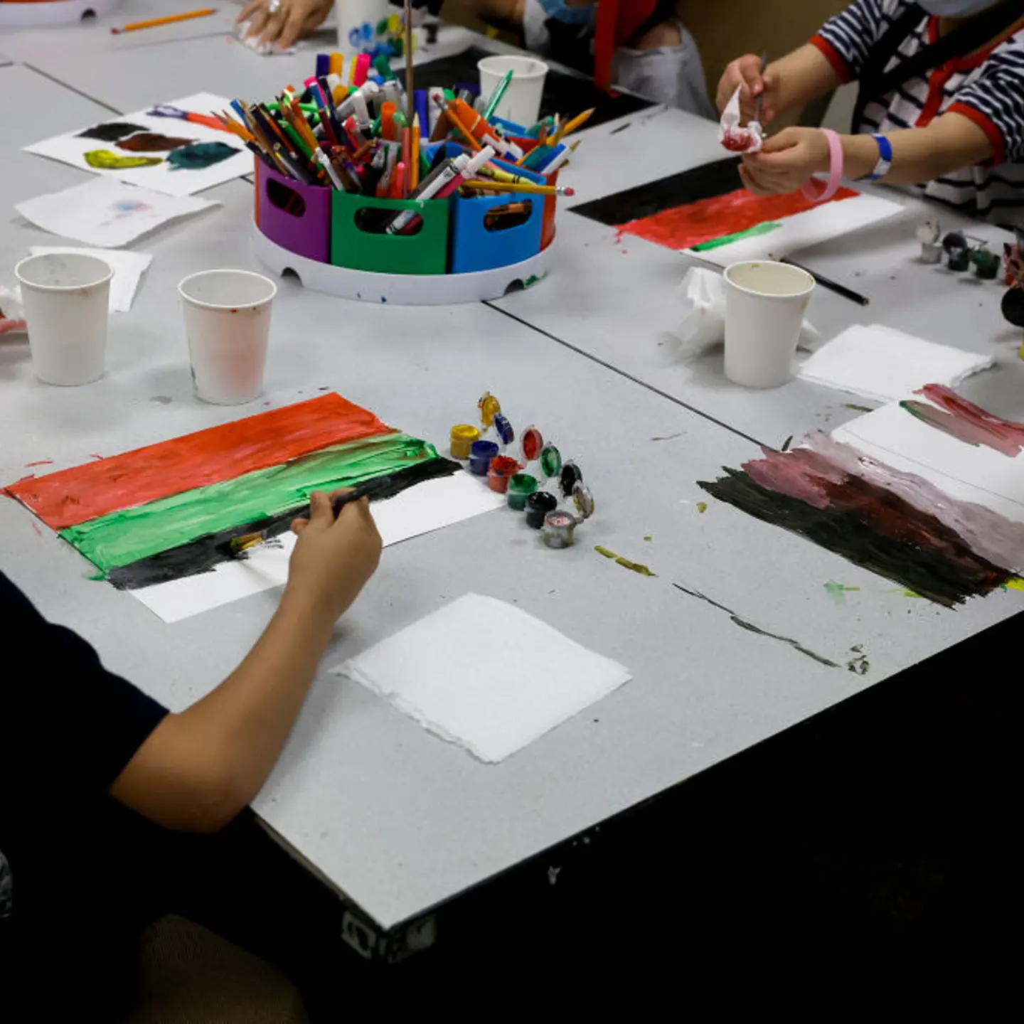 Young Afghan children paint a piece of paper with the colors of the national flag of Afghanistan in an art class at the National Conference Center in Leesburg, Virginia.