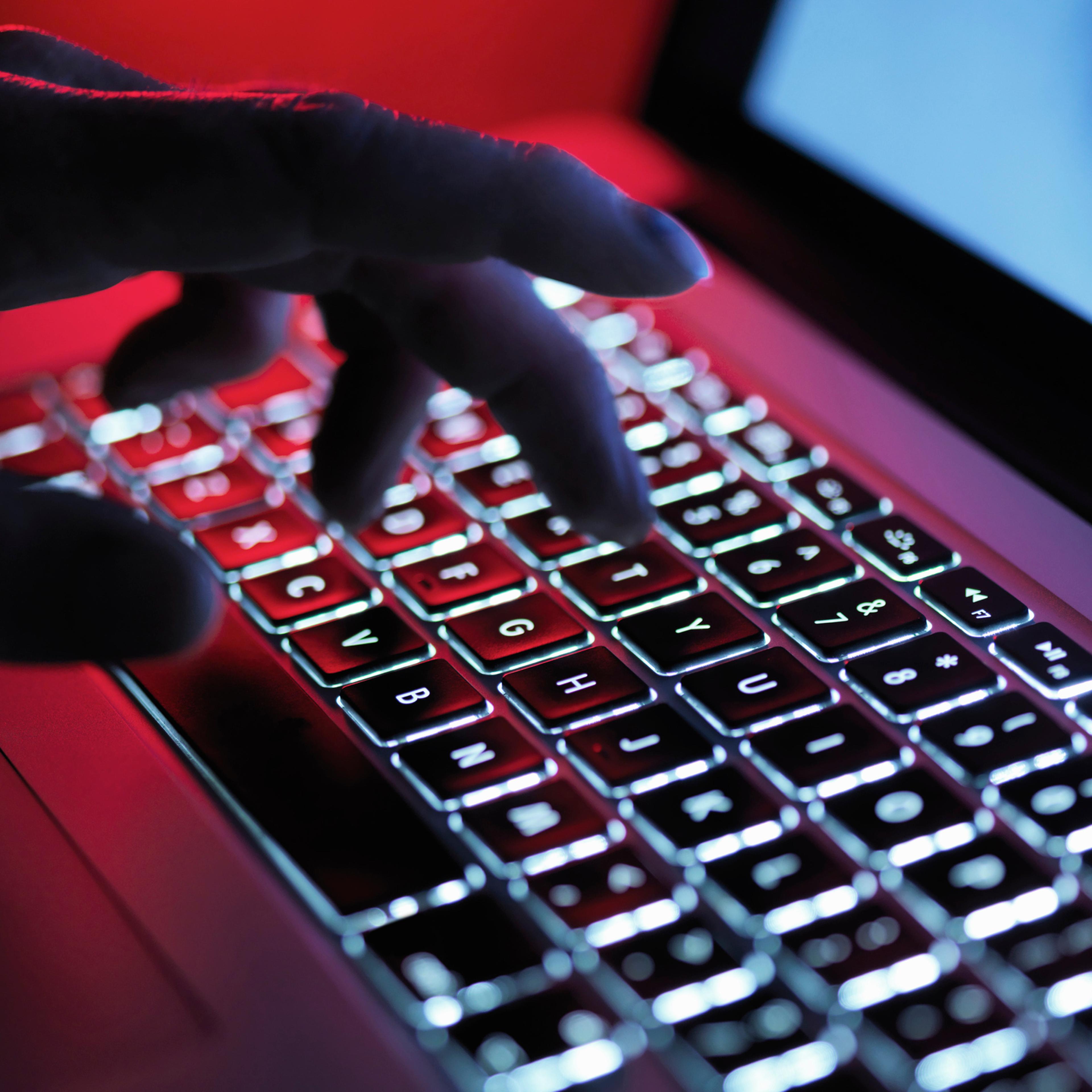 A dark mystery hand typing on a laptop computer at night