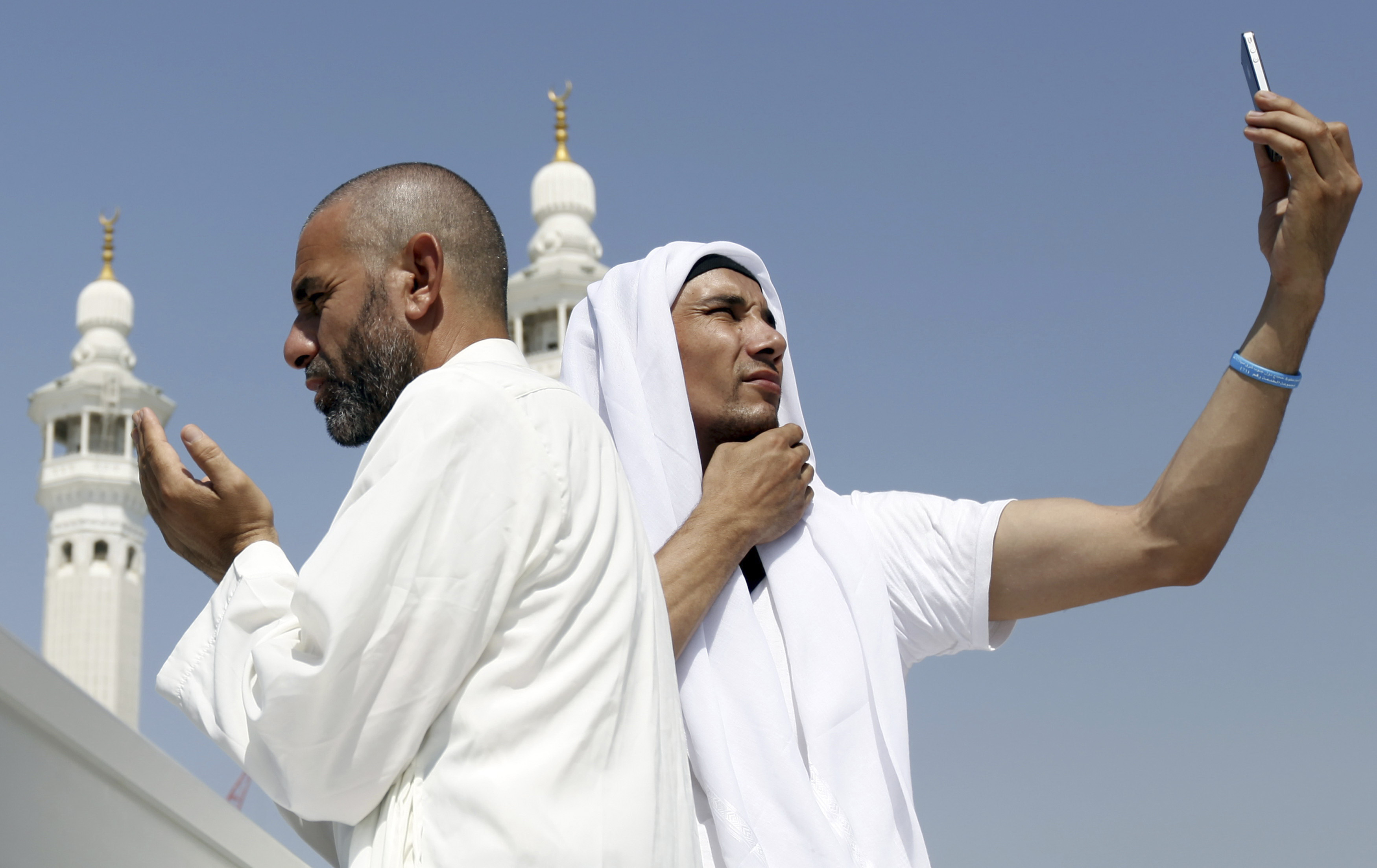 A Muslim pilgrim prays as another takes a photo with his mobile phone at the Grand Mosque during Tawaf al-Wadaa (Farewell Tawaf) on the last day of the annual haj pilgrimage in the holy city of Mecca on Oct. 29, 2012.