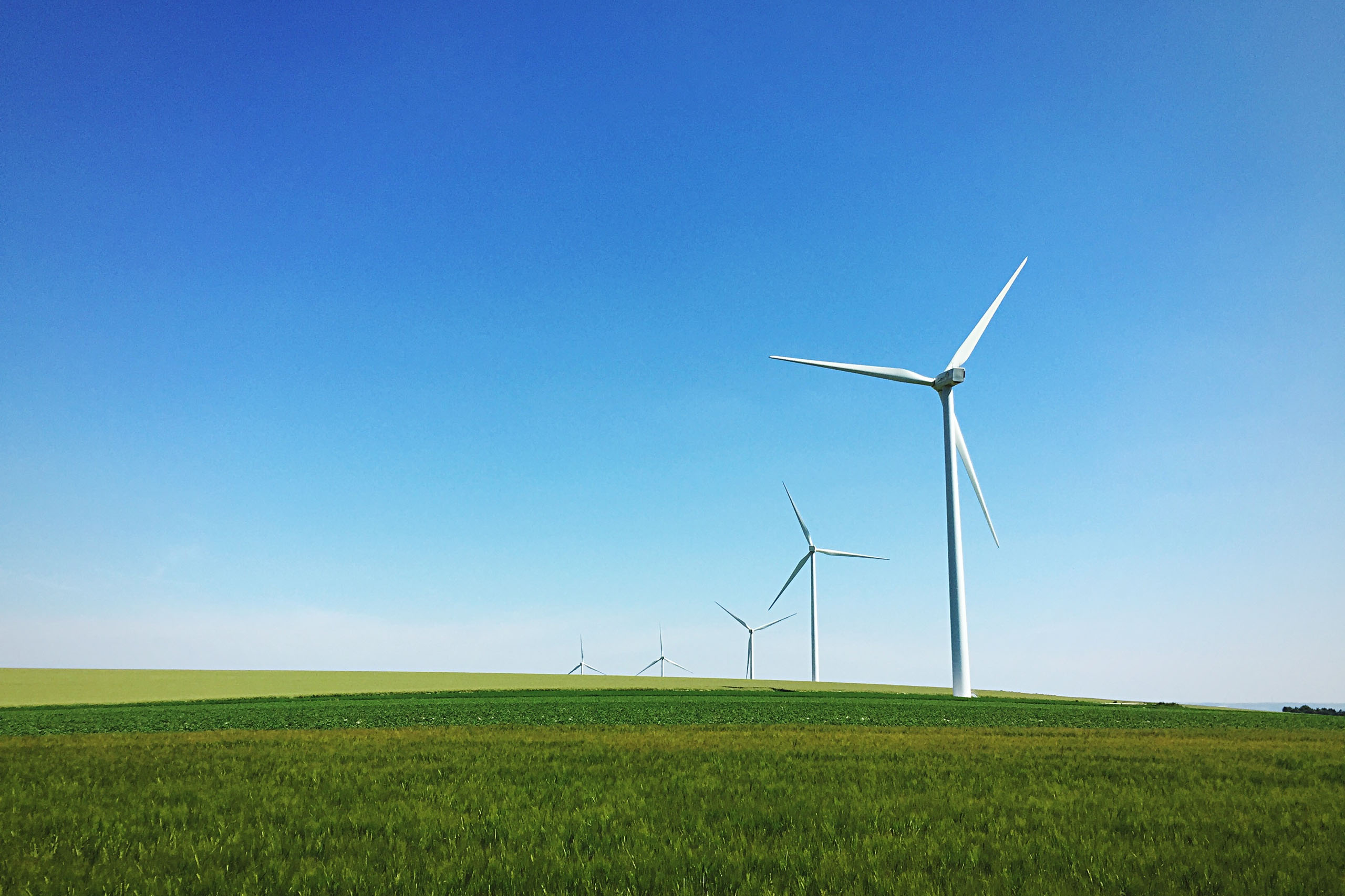 Windmills On Grassy Field Against Sky