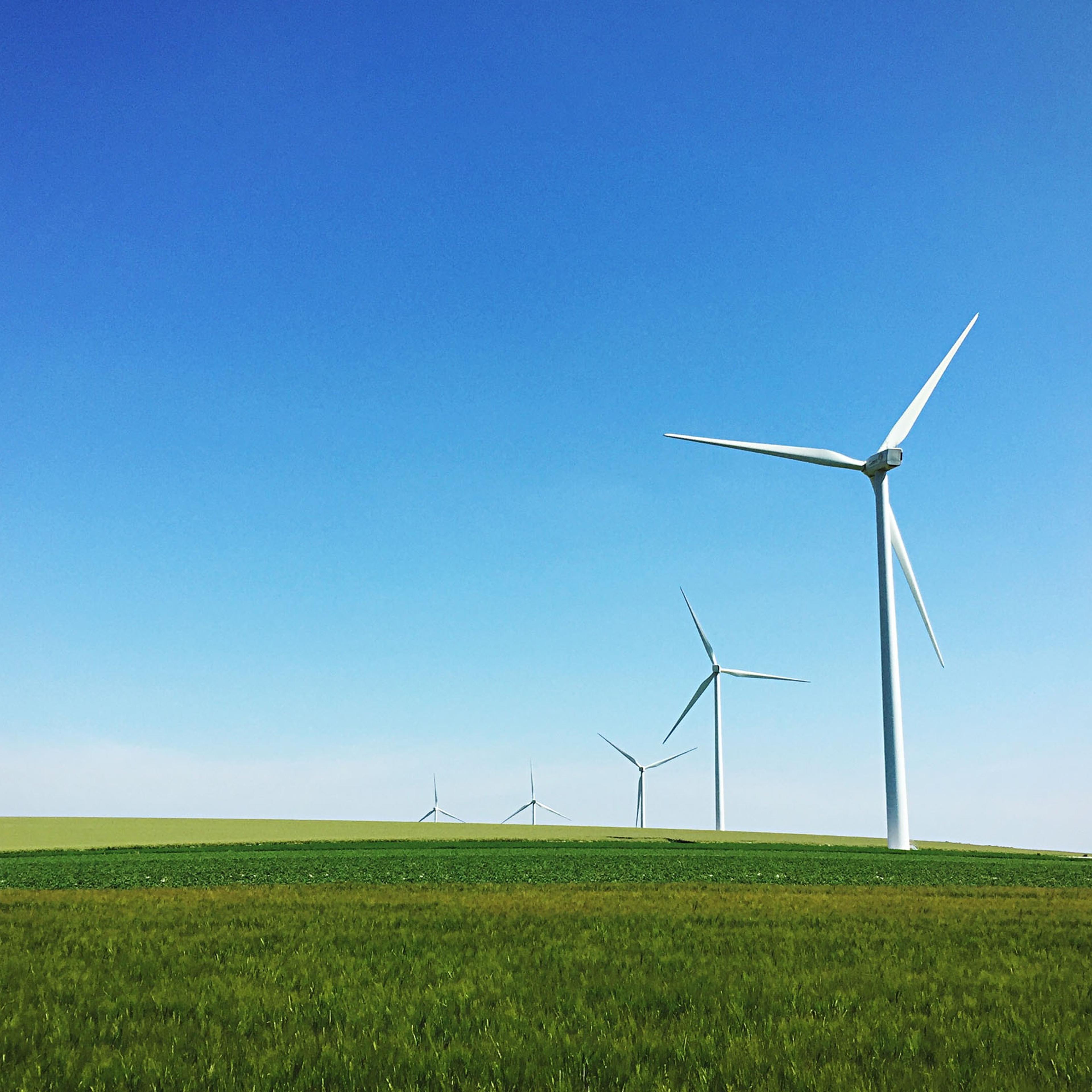 Windmills On Grassy Field Against Sky