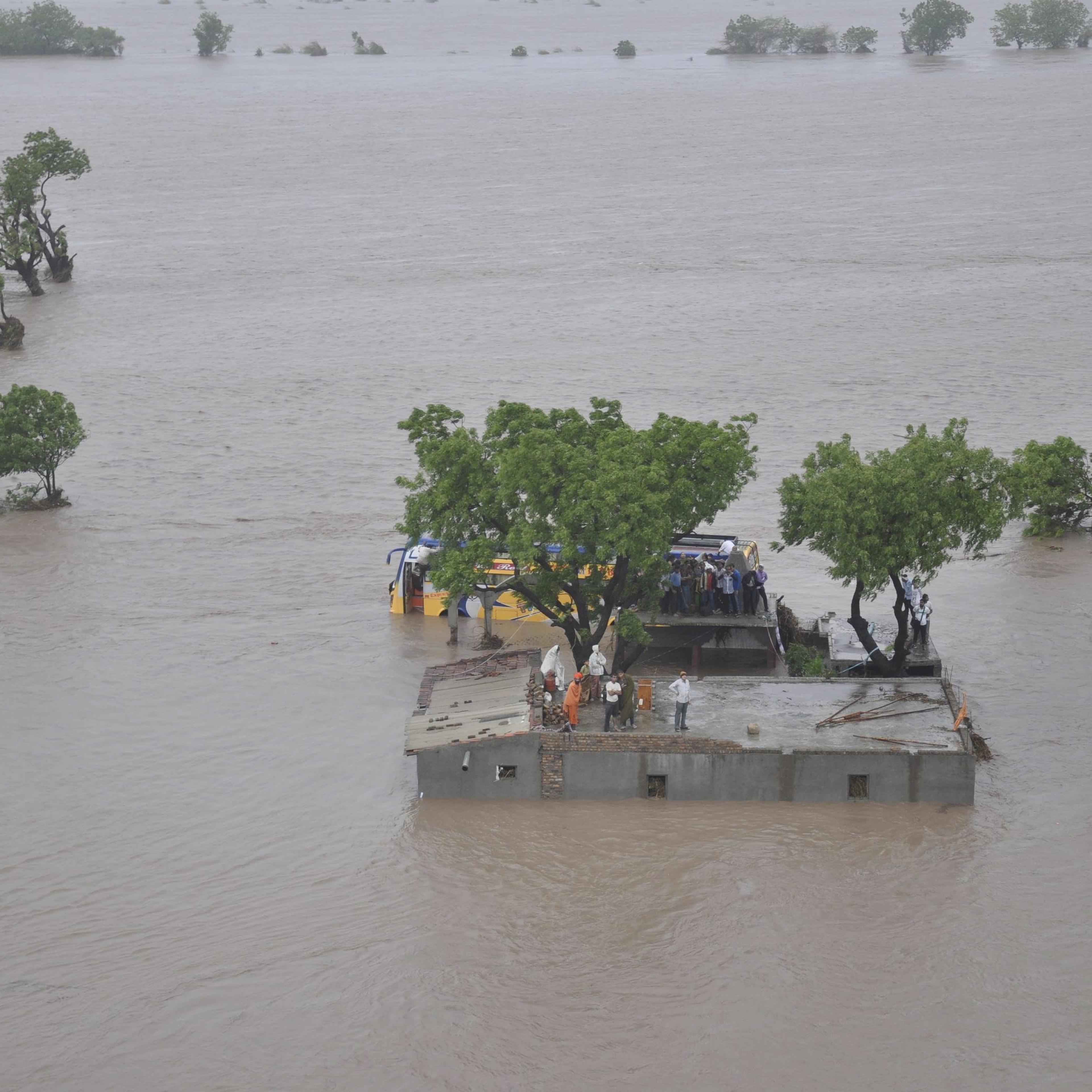 An aerial view shows flood victims standing atop their submerged houses in Amreli