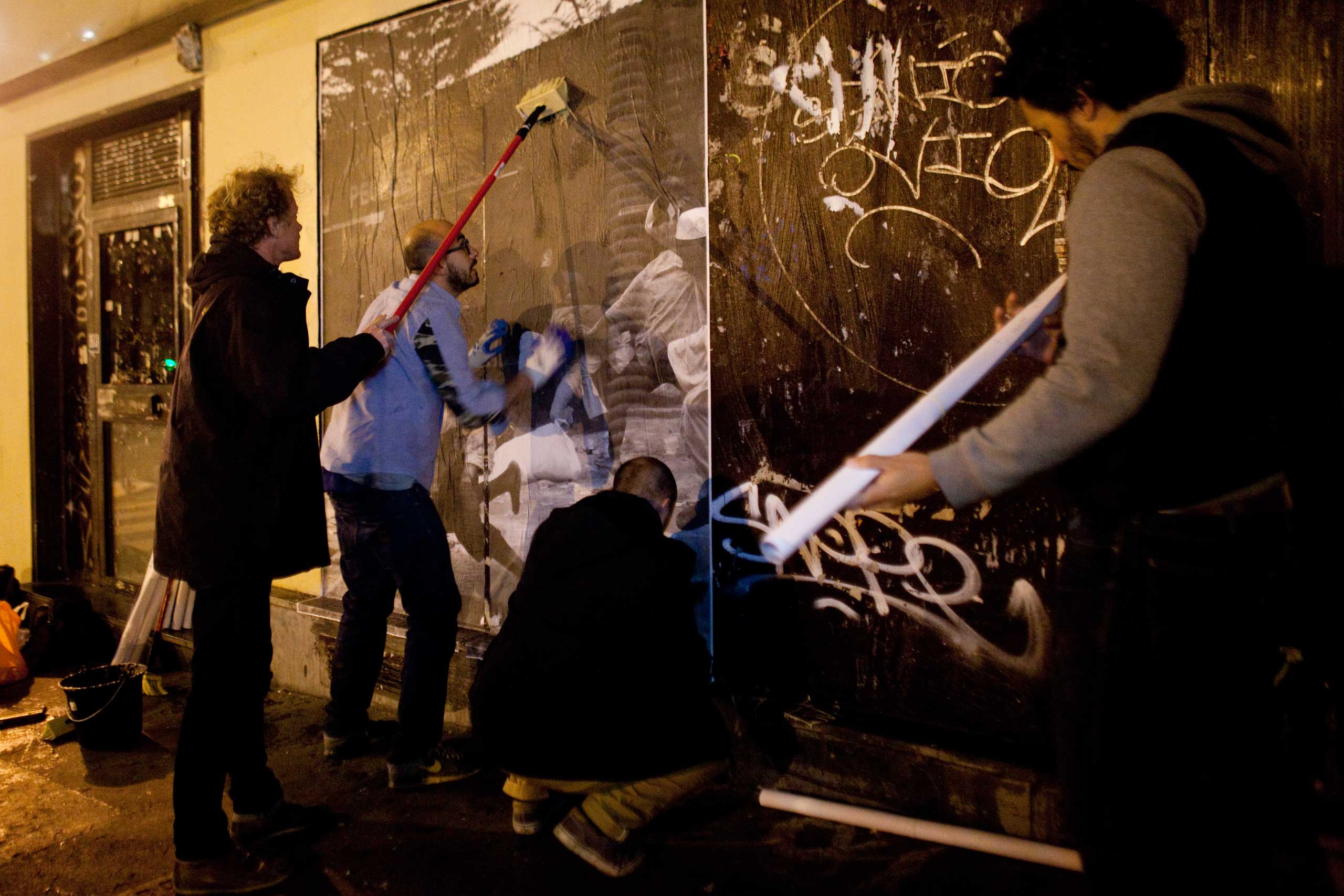 Photographer Pierre Terdjman puts up one of his images on a Parisian wall.