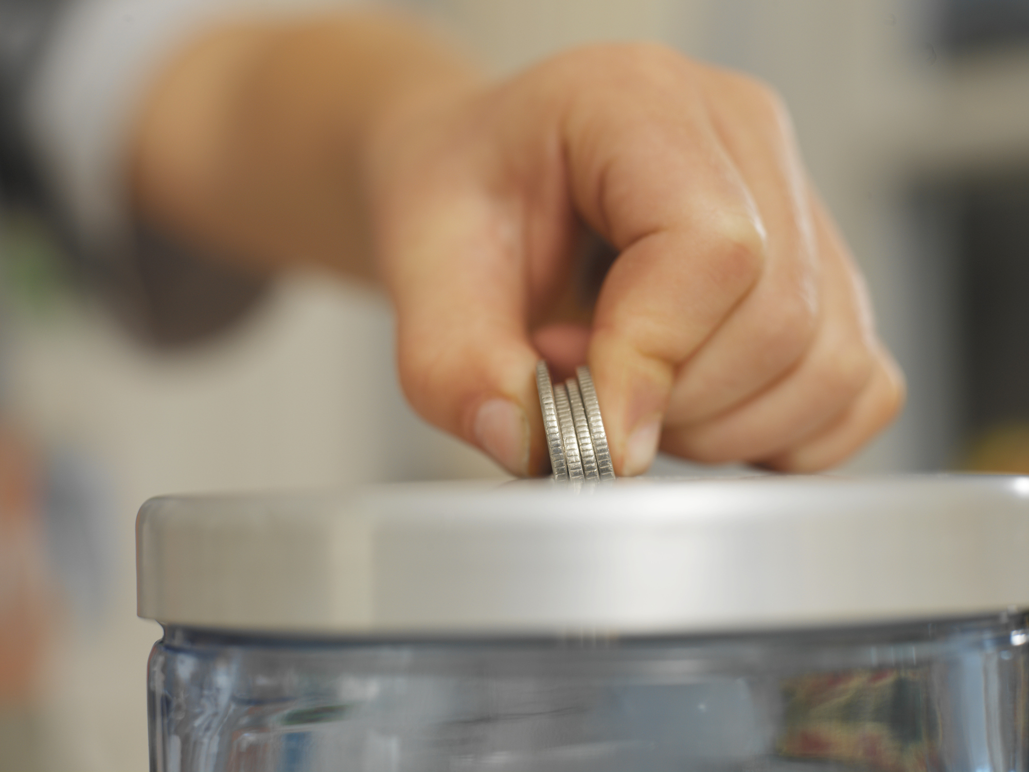 Boy placing coins in money jar, close-up