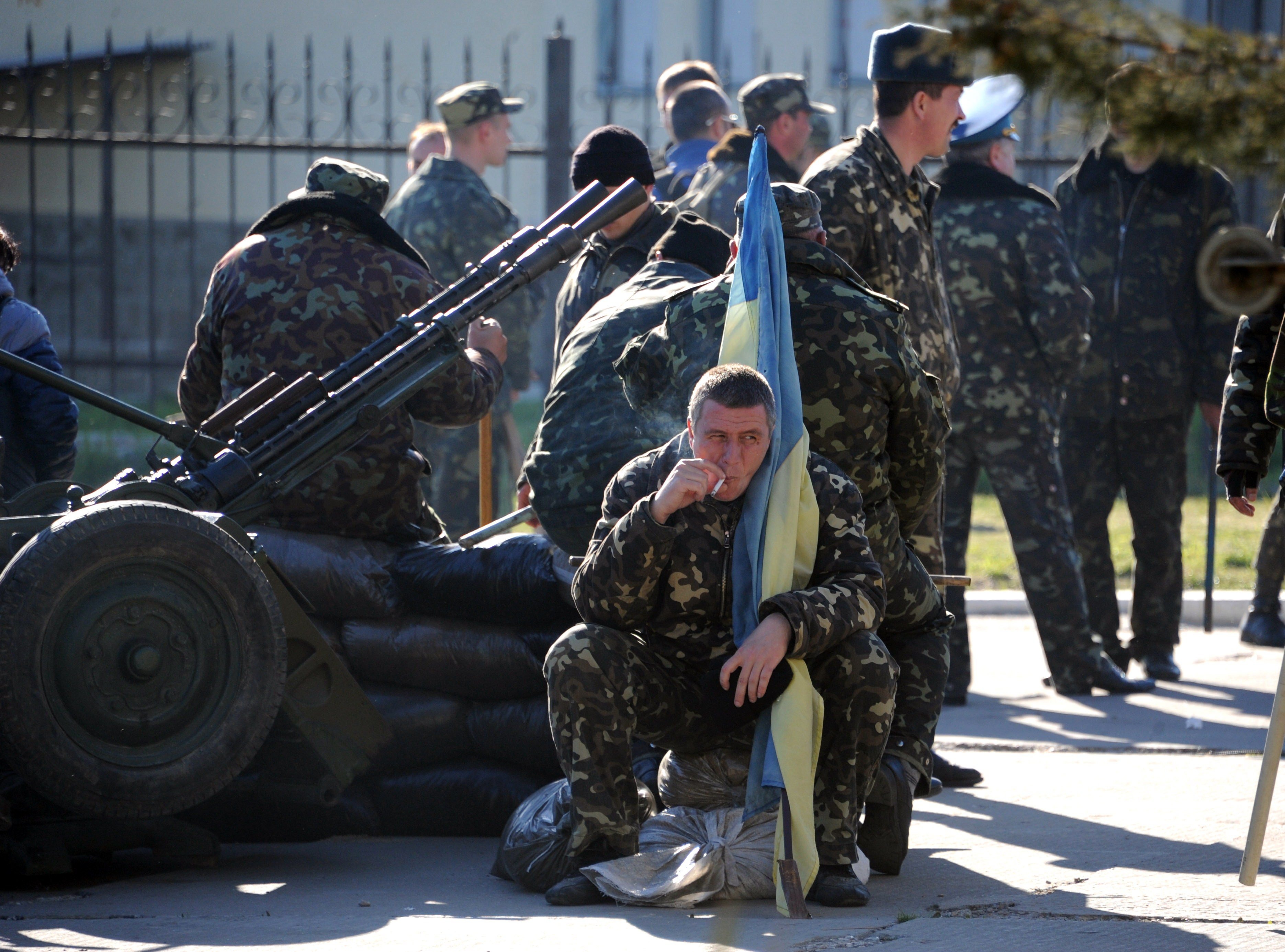 A Ukrainian officer holds his flag as he smokes a cigarette before pro-Russia militia and Russian armed forces backed by armoured vehicles broke inside the Ukrainian airbase in the small city of Belbek near the Crimean city of Sevastopol on March 22, 201