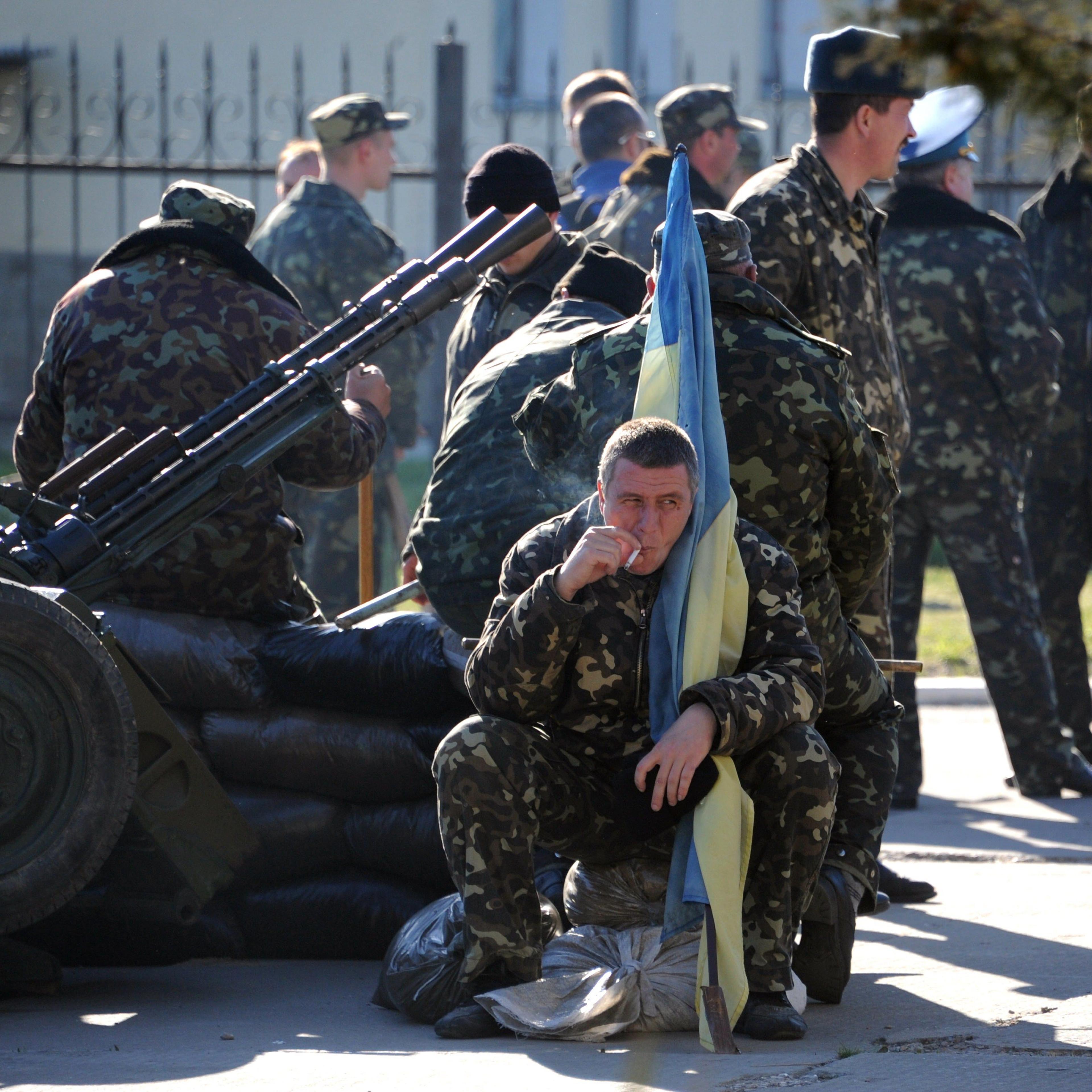 A Ukrainian officer holds his flag as he smokes a cigarette before pro-Russia militia and Russian armed forces backed by armoured vehicles broke inside the Ukrainian airbase in the small city of Belbek near the Crimean city of Sevastopol on March 22, 201