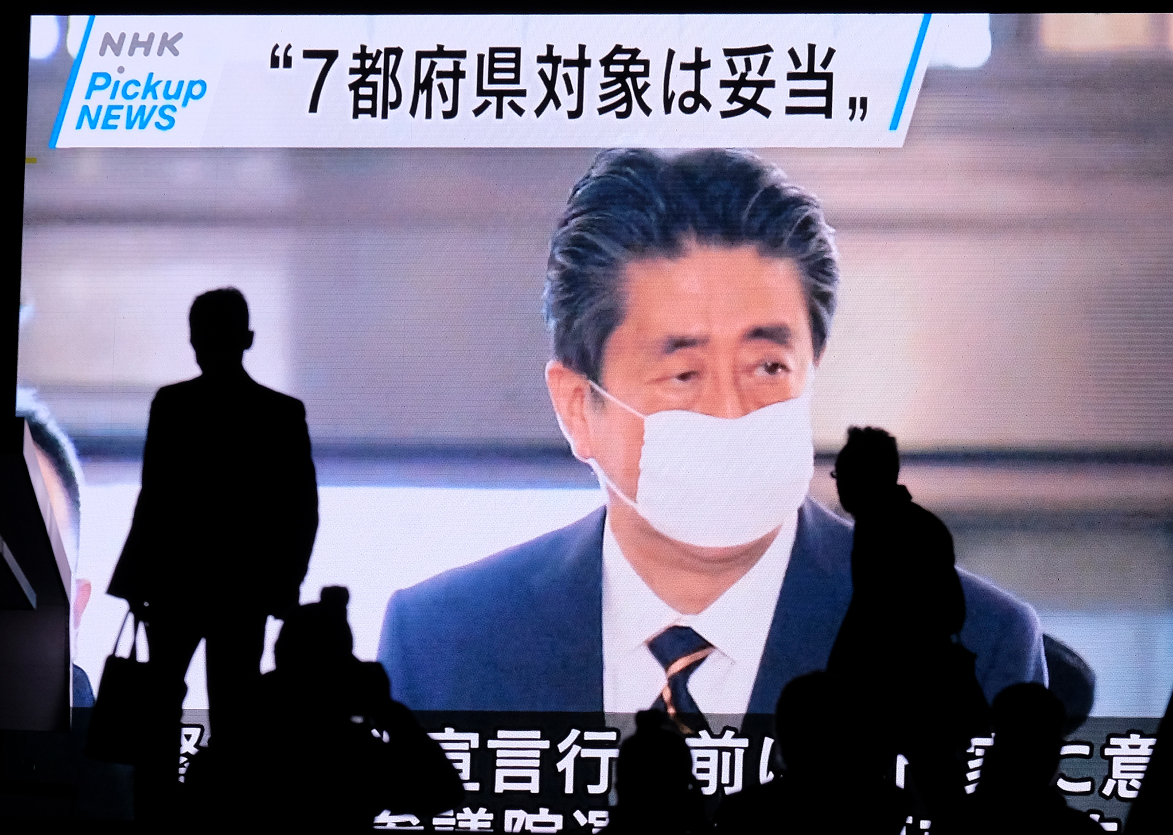 A screen displays news footage of Japan's Prime Minister Shinzo Abe at parliament in Tokyo on April 7