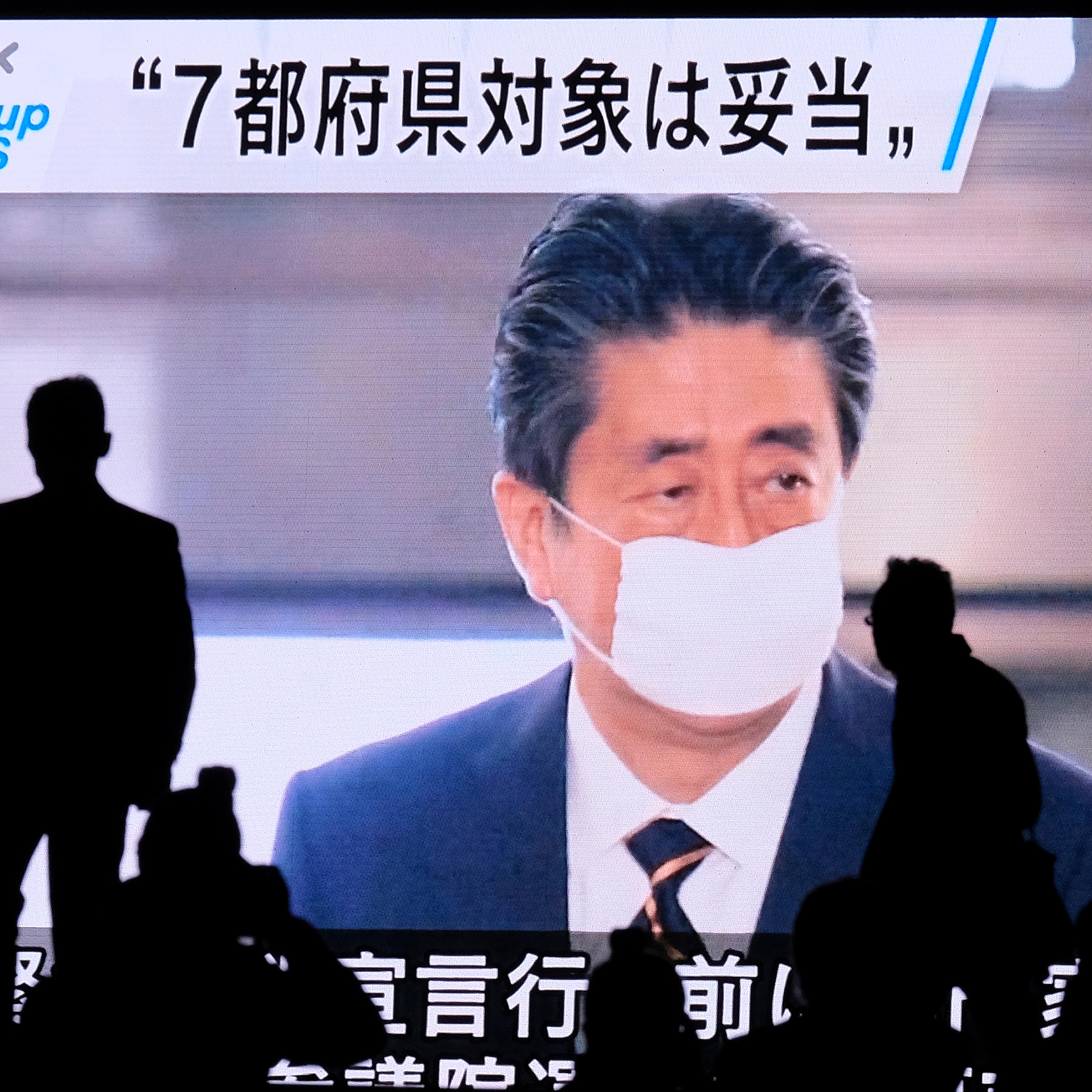 A screen displays news footage of Japan's Prime Minister Shinzo Abe at parliament in Tokyo on April 7
