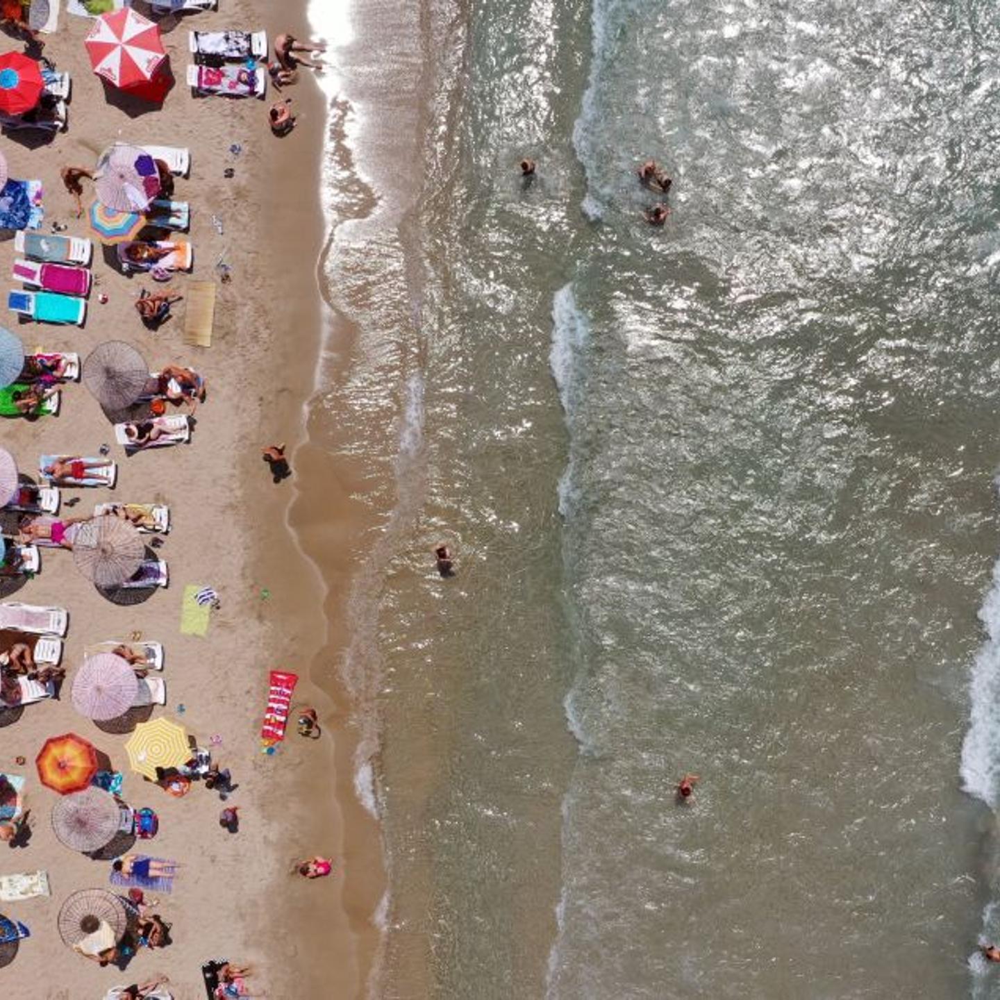 An aerial view of sunbathers under colorful parasols in Aydin, Turkey on July 23, 2019.
