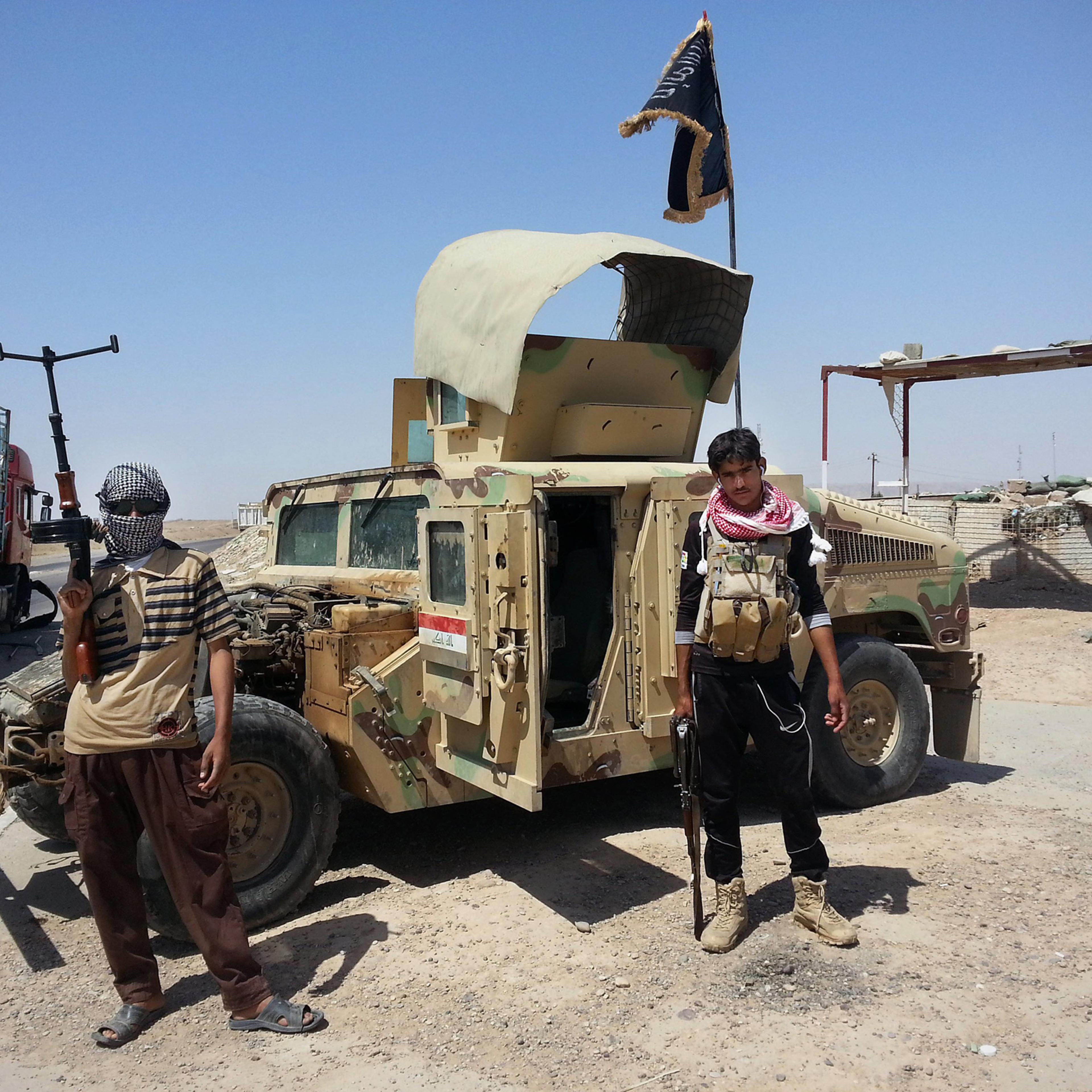 Al-Qaeda inspired militants stand with captured Iraqi Army Humvee at a checkpoint belonging to Iraqi Army outside Beiji refinery some 155 miles north of Baghdad, June 19, 2014.