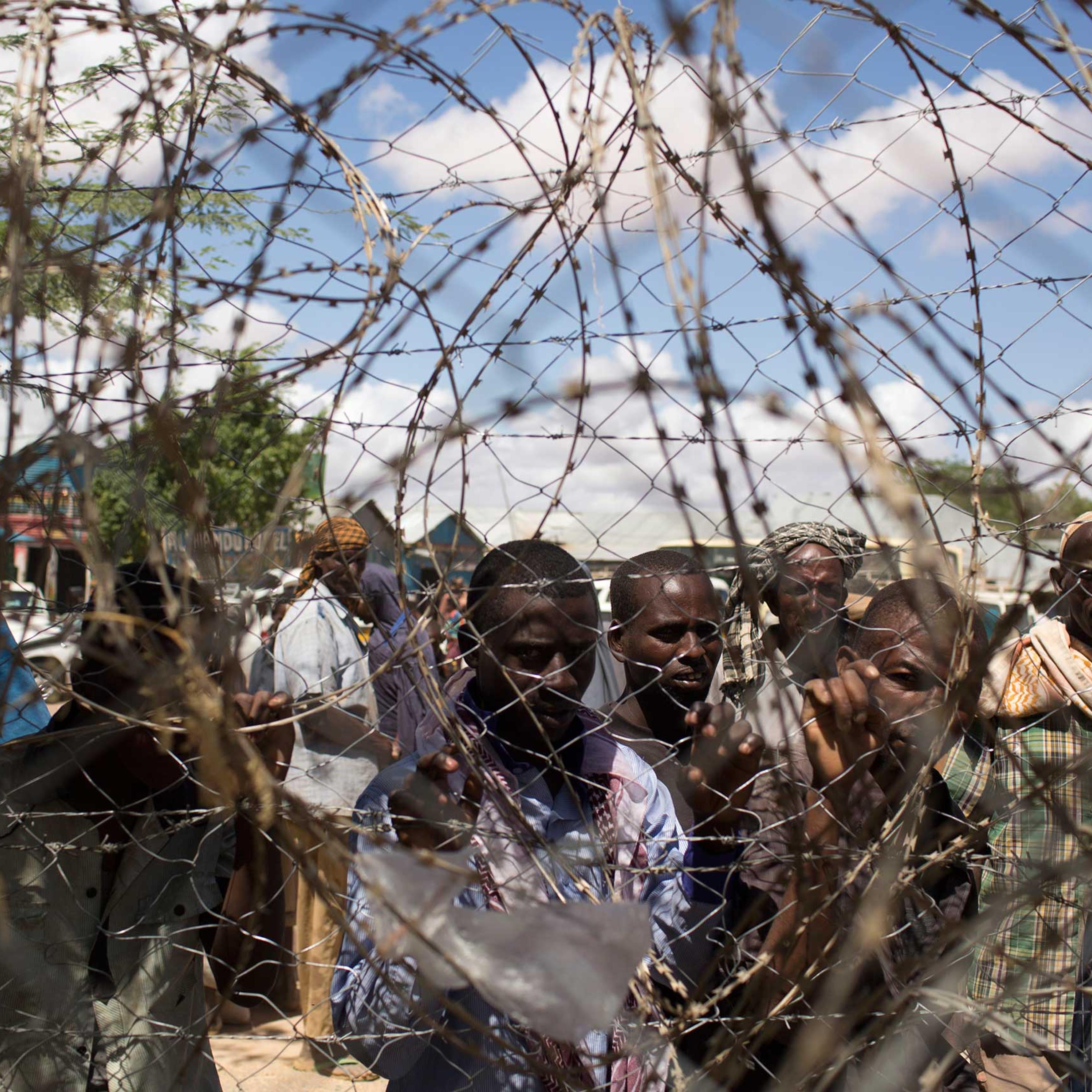Somali refugees look through a barbwire fence in Dagahale, one of the several refugee settlements in Dadaab, Garissa County, northeastern Kenya in 2013.