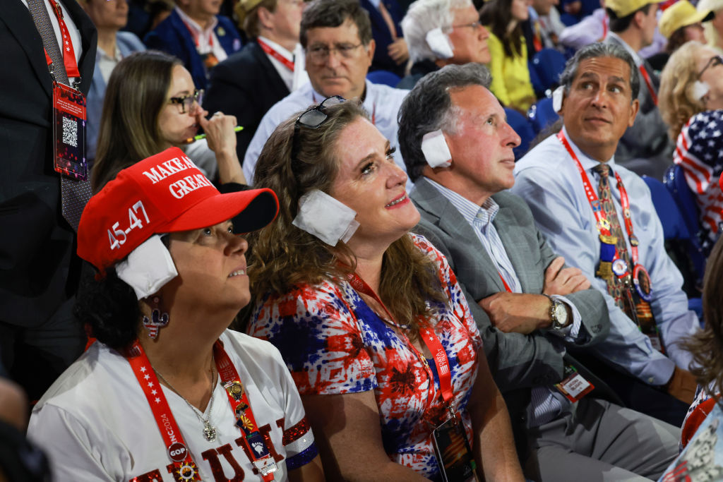 People wear fake bandages on their ears as they watch on the third day of the Republican National Convention at the Fiserv Forum in Milwaukee, Wisconsin, on July 17, 2024.
