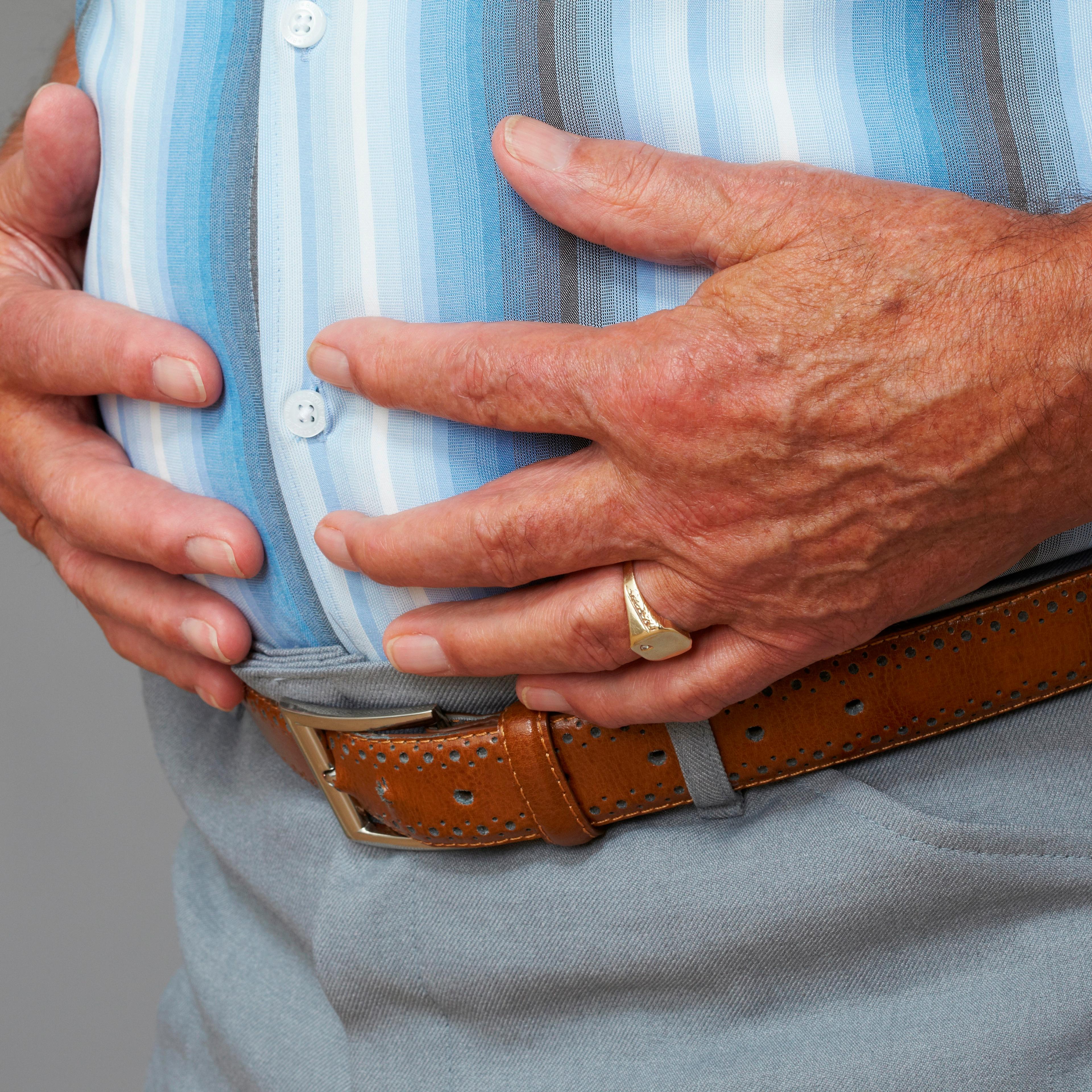 Overweight senior man touching stomach