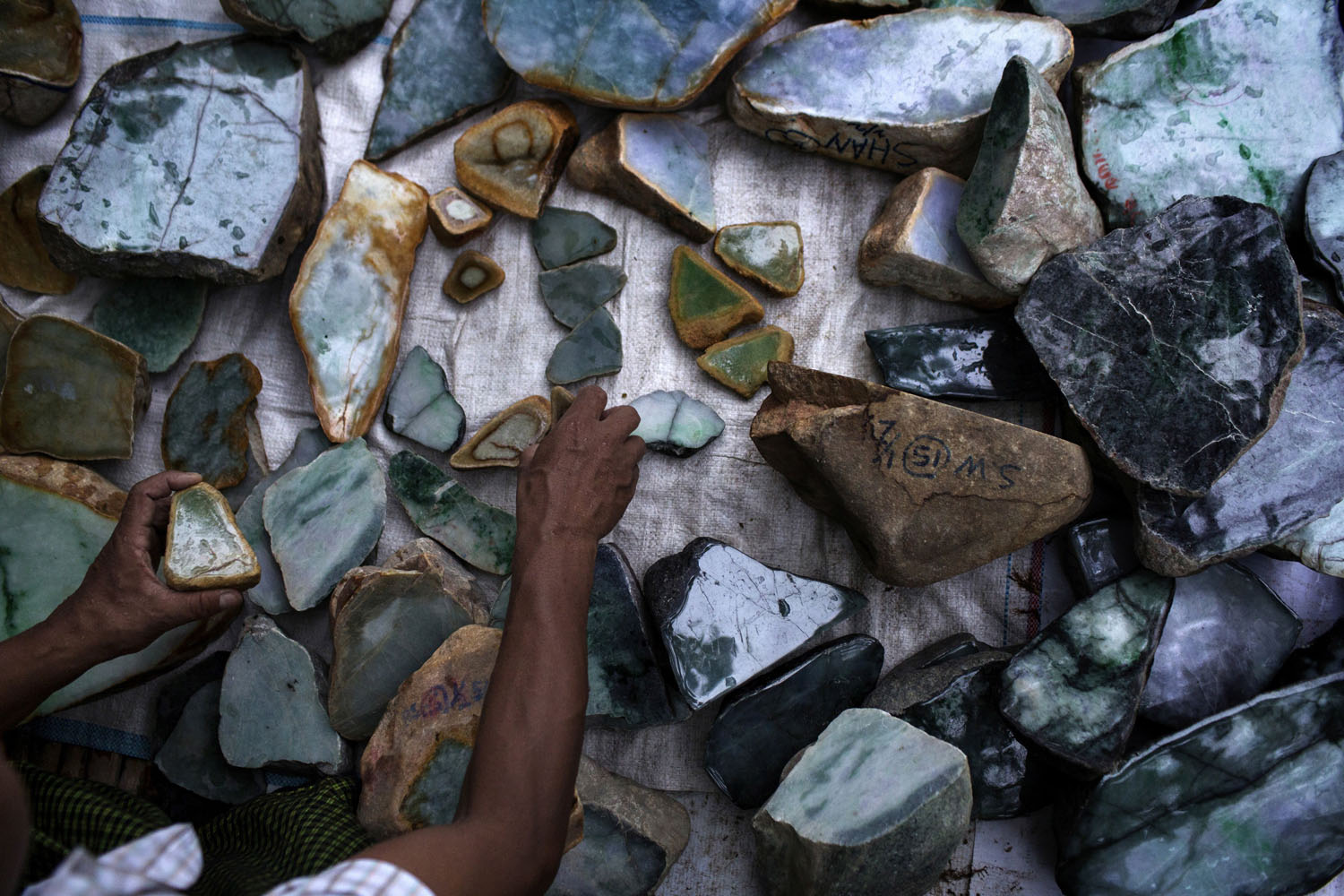 A Burmese dealer arranges chunks of jade at a market stall in Mandalay.