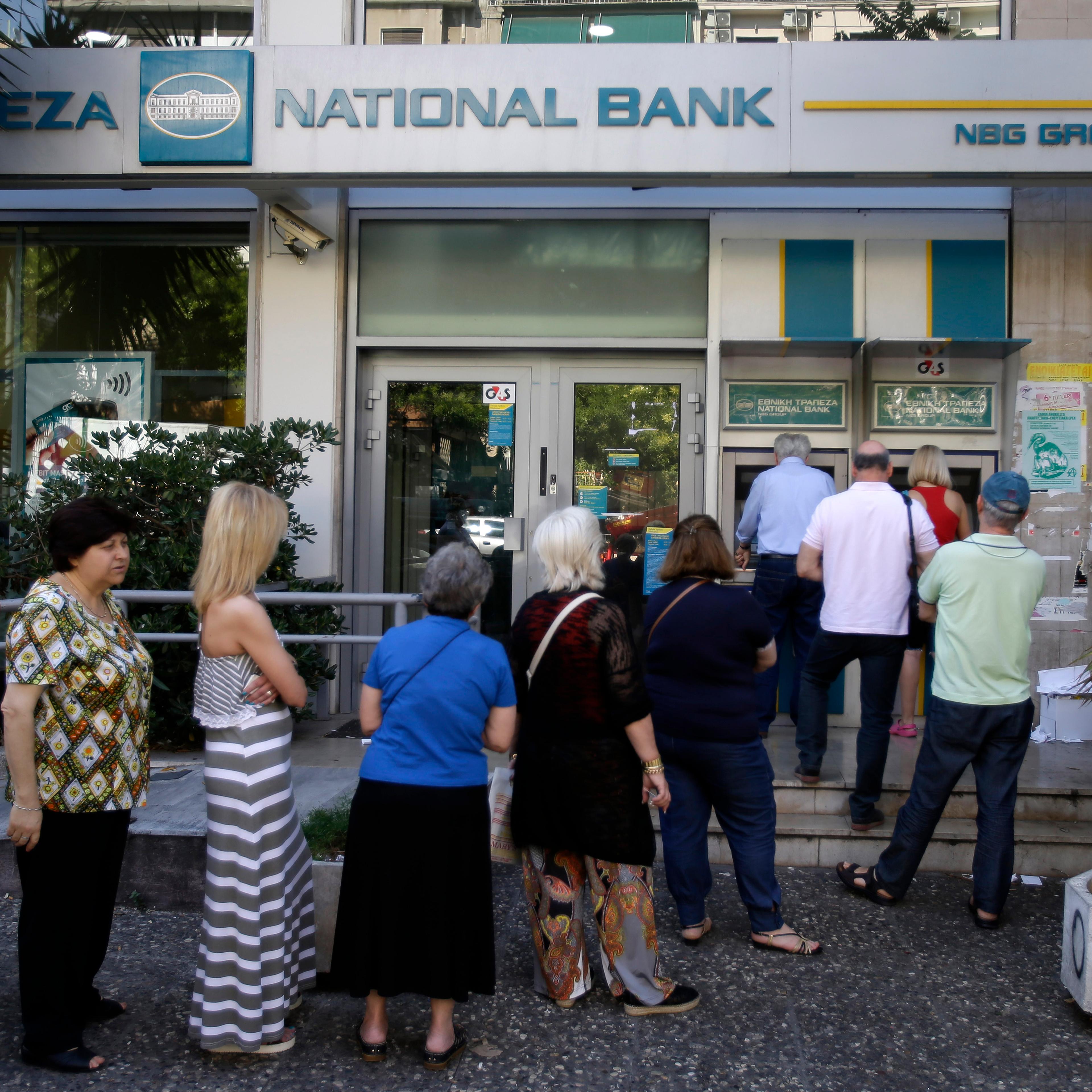 People stand in a queue to use an ATM outside a closed bank in Athens on June 30, 2015.